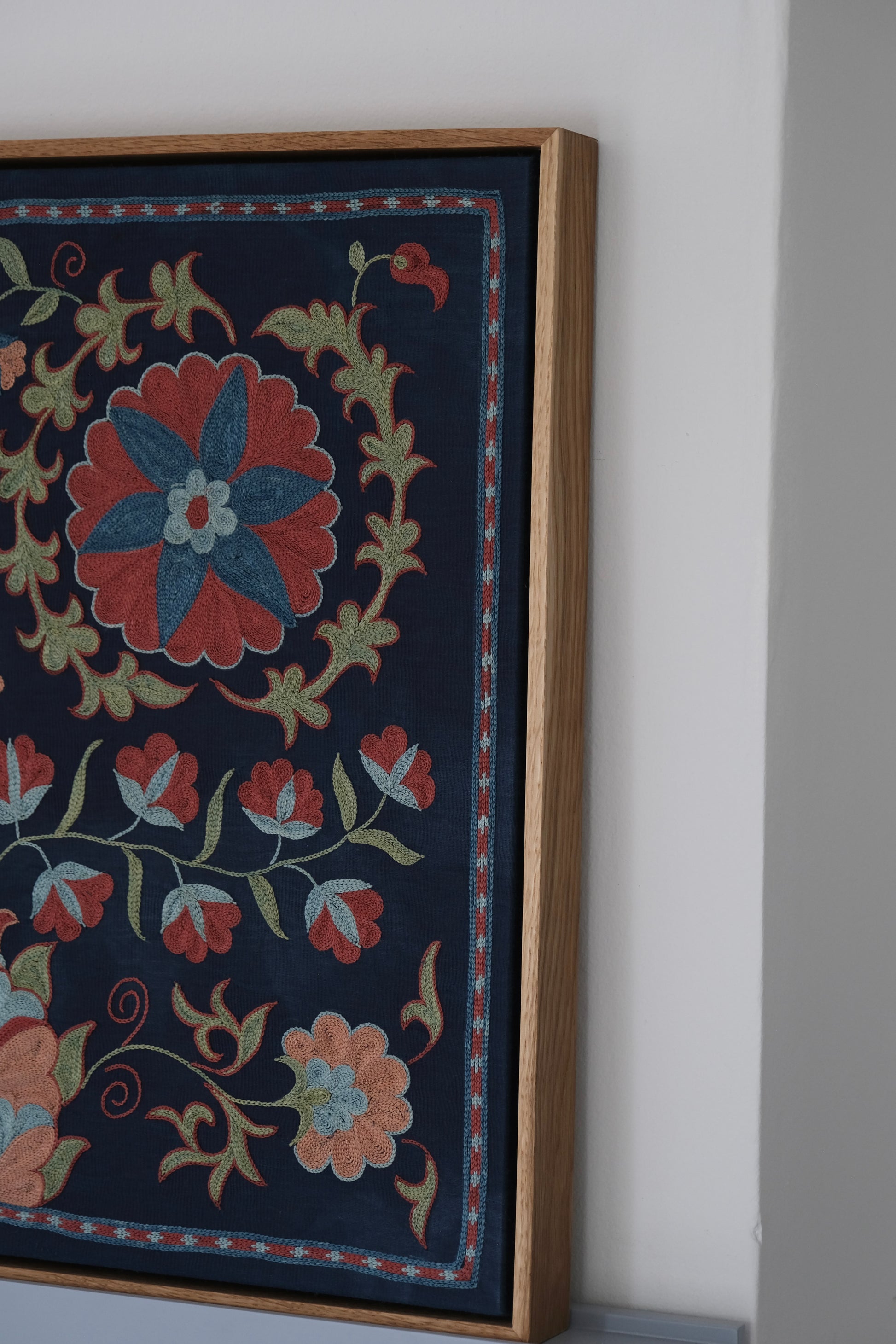 Framed suzani, embroidered textile art, wooden frame, navy blue with floral motifs, side view