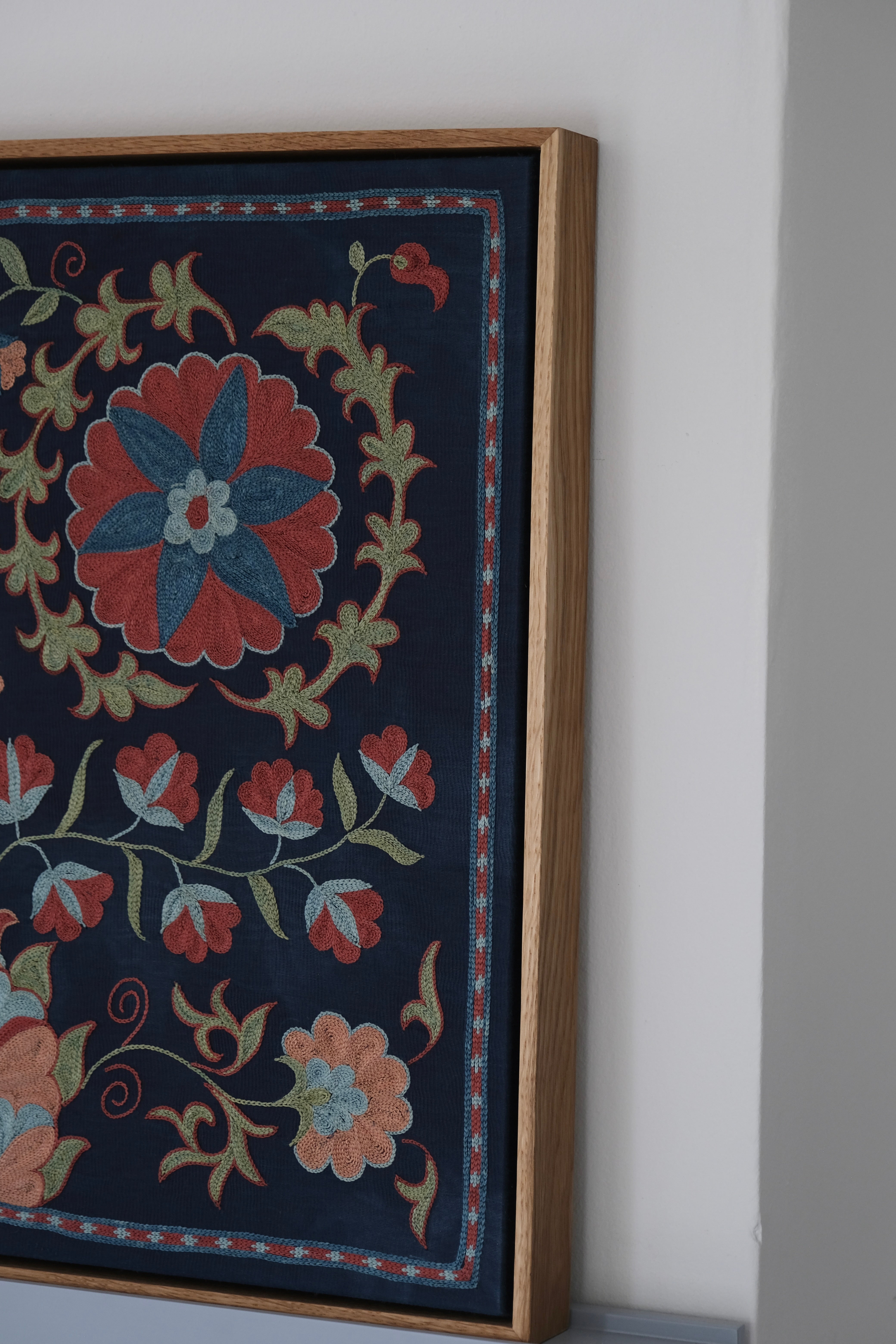 Framed suzani, embroidered textile art, wooden frame, navy blue with floral motifs, side view