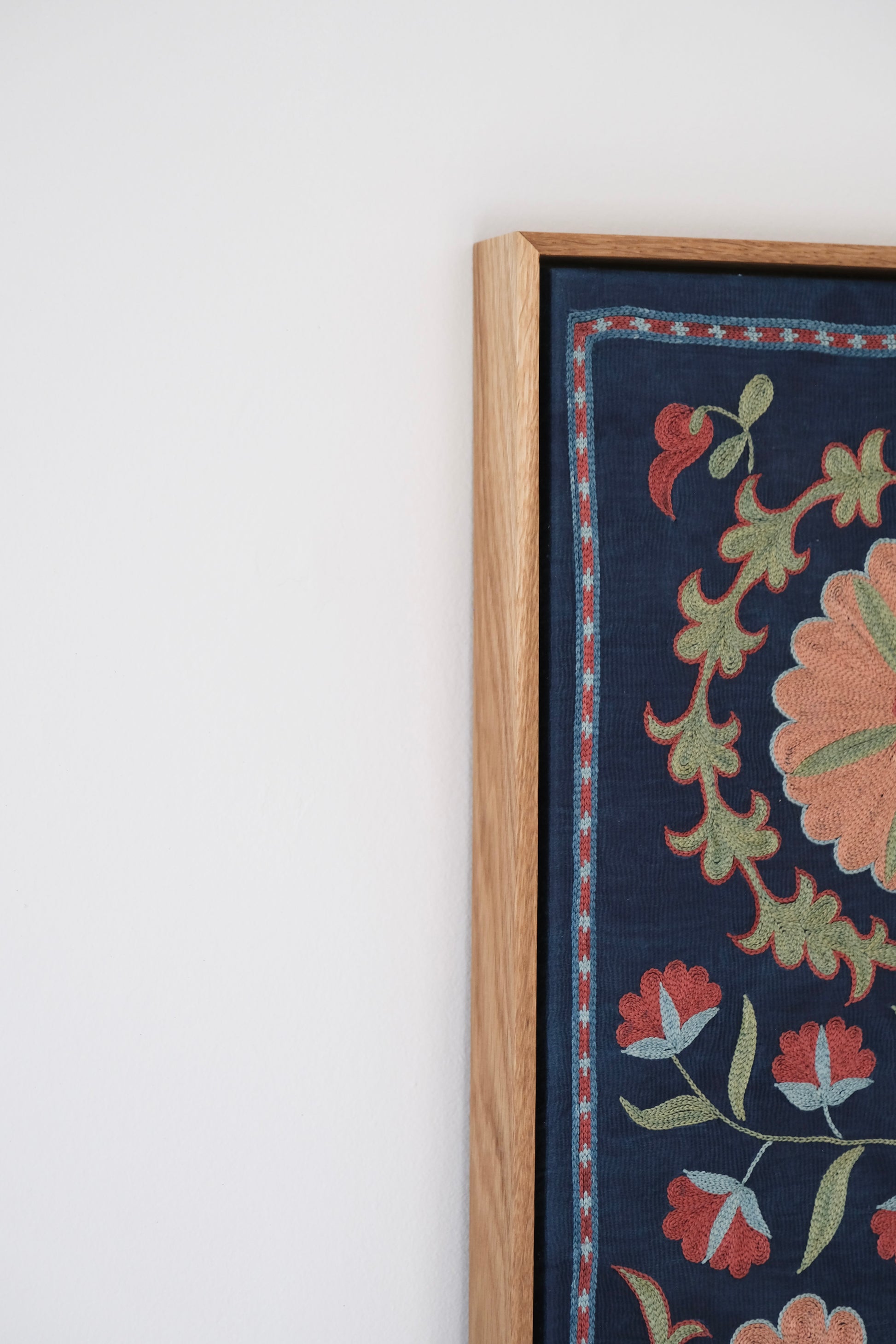 Framed suzani, embroidered textile art, wooden frame, navy blue with floral motifs, side view