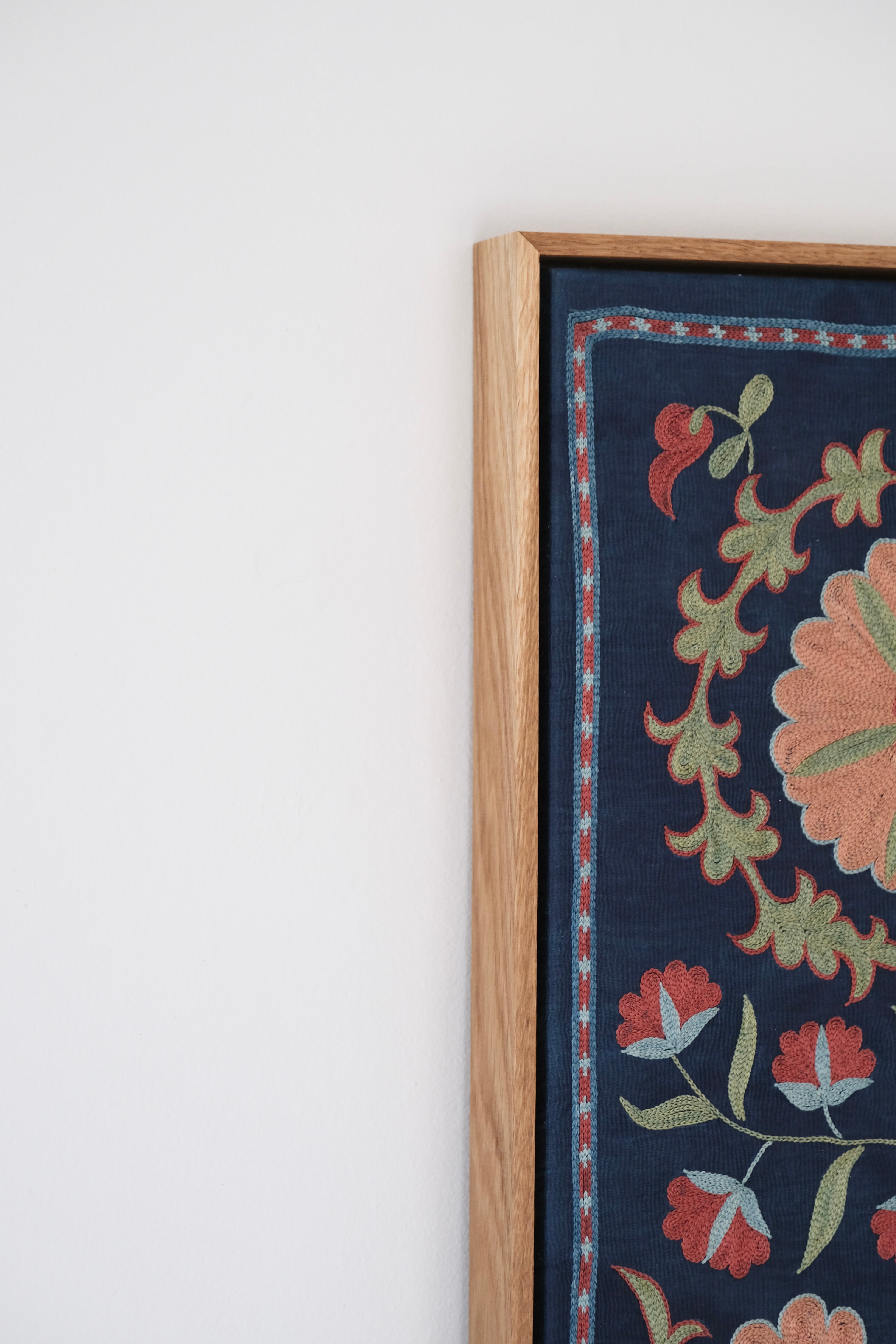 Framed suzani, embroidered textile art, wooden frame, navy blue with floral motifs, side view