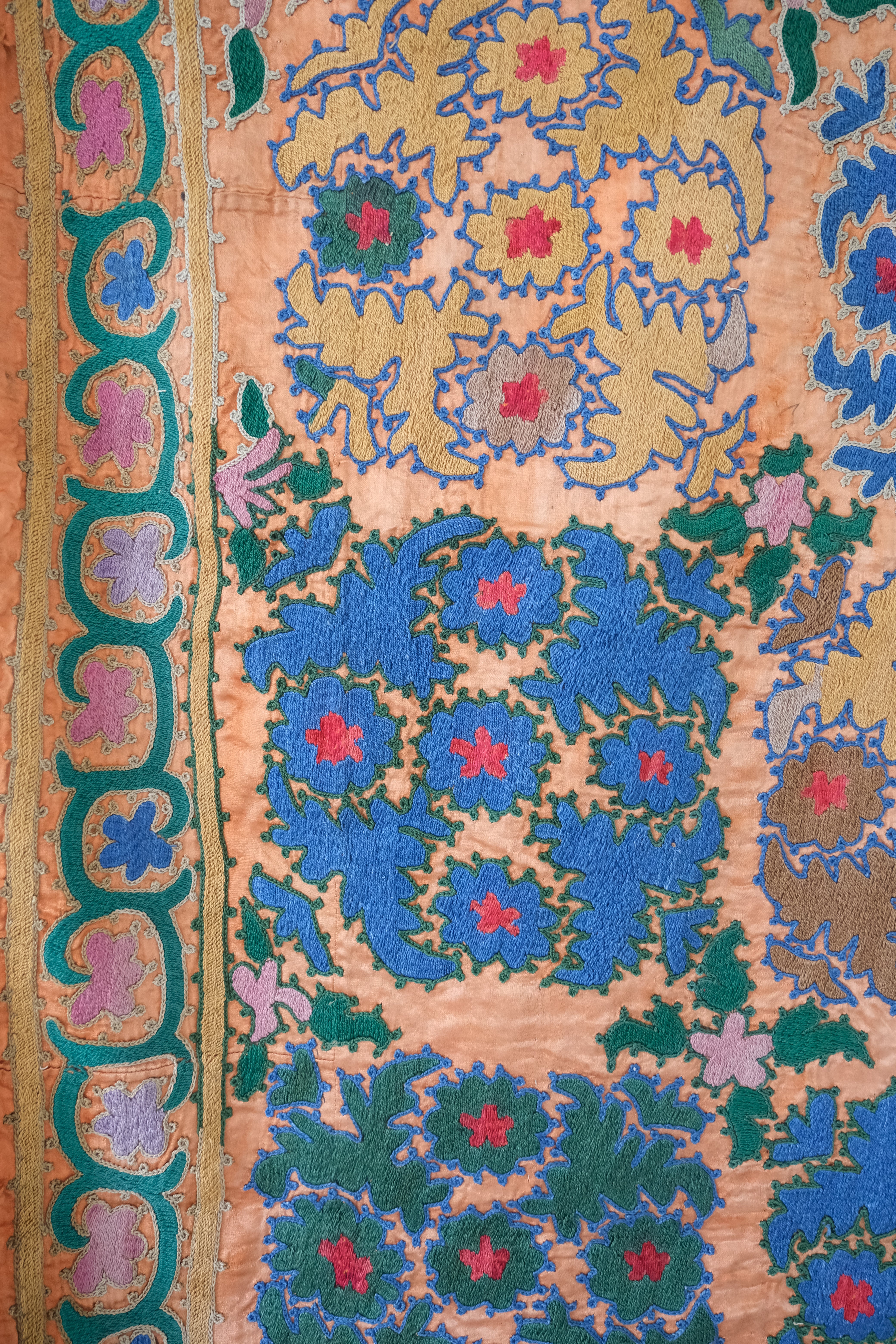 Vintage suzani, silk embroidered textile, orange and floral design, close-up