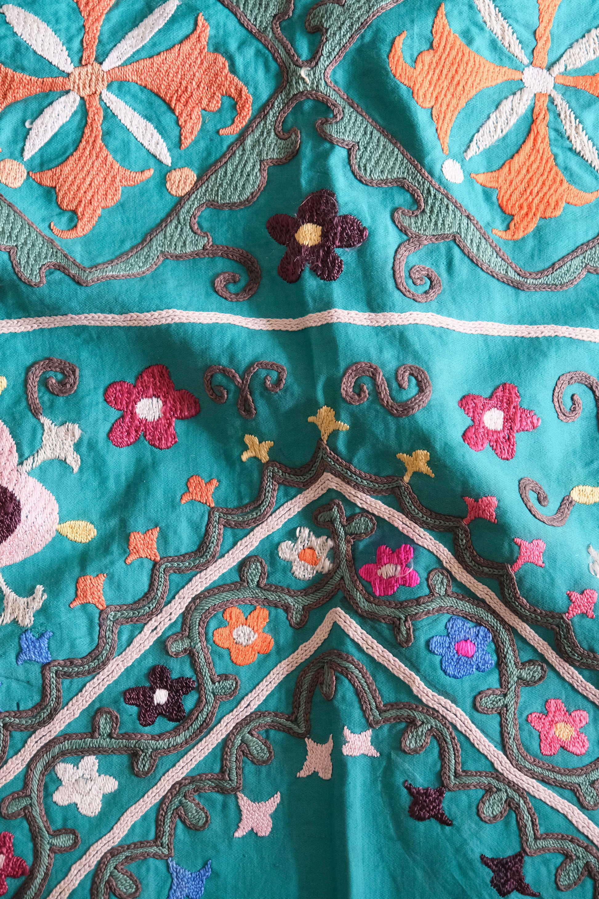 Vintage suzani, colourful embroidered textile, turquoise with flowers, close-up