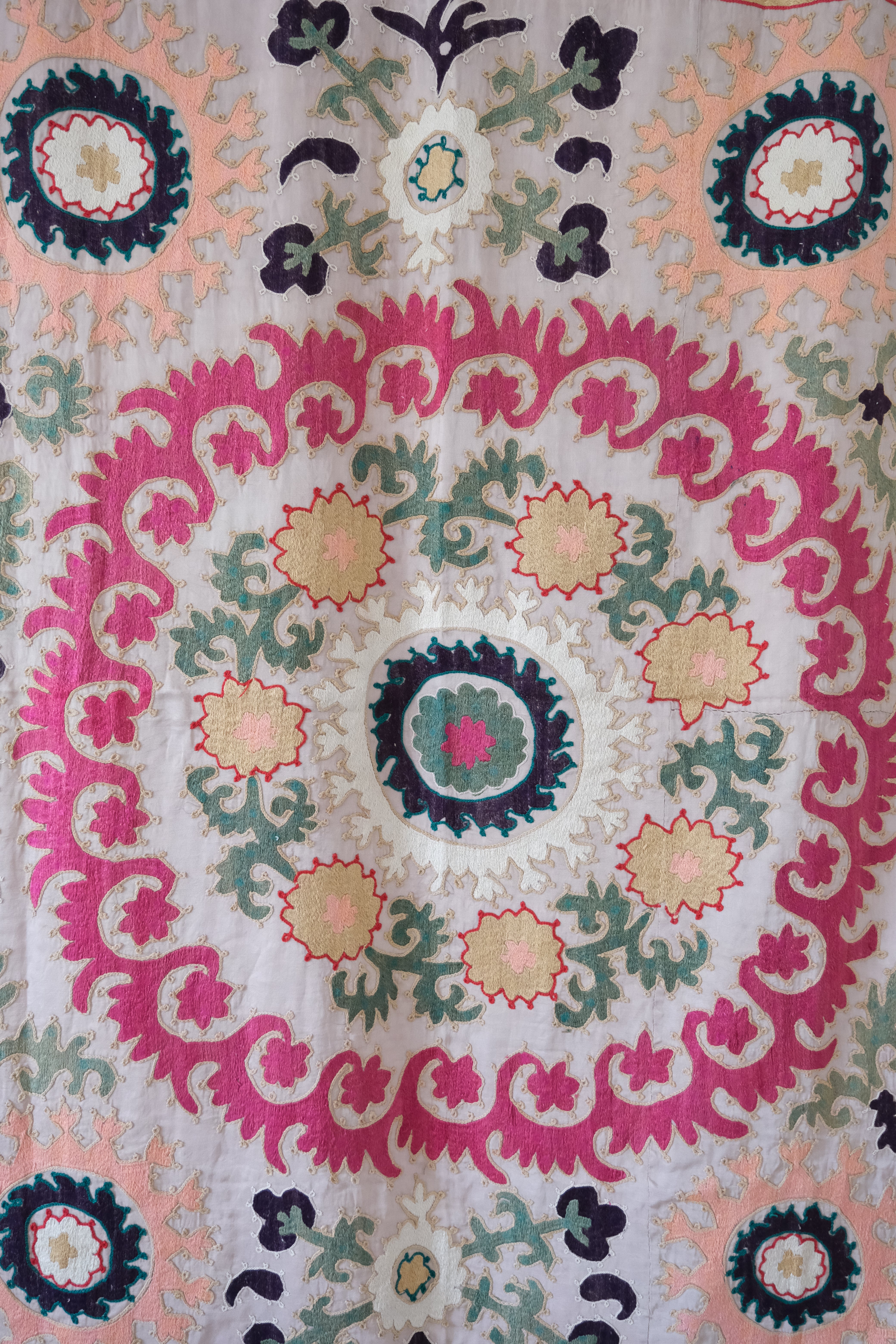 Vintage suzani, decorative embroidered tapestry, pink with geometric and floral design, close-up
