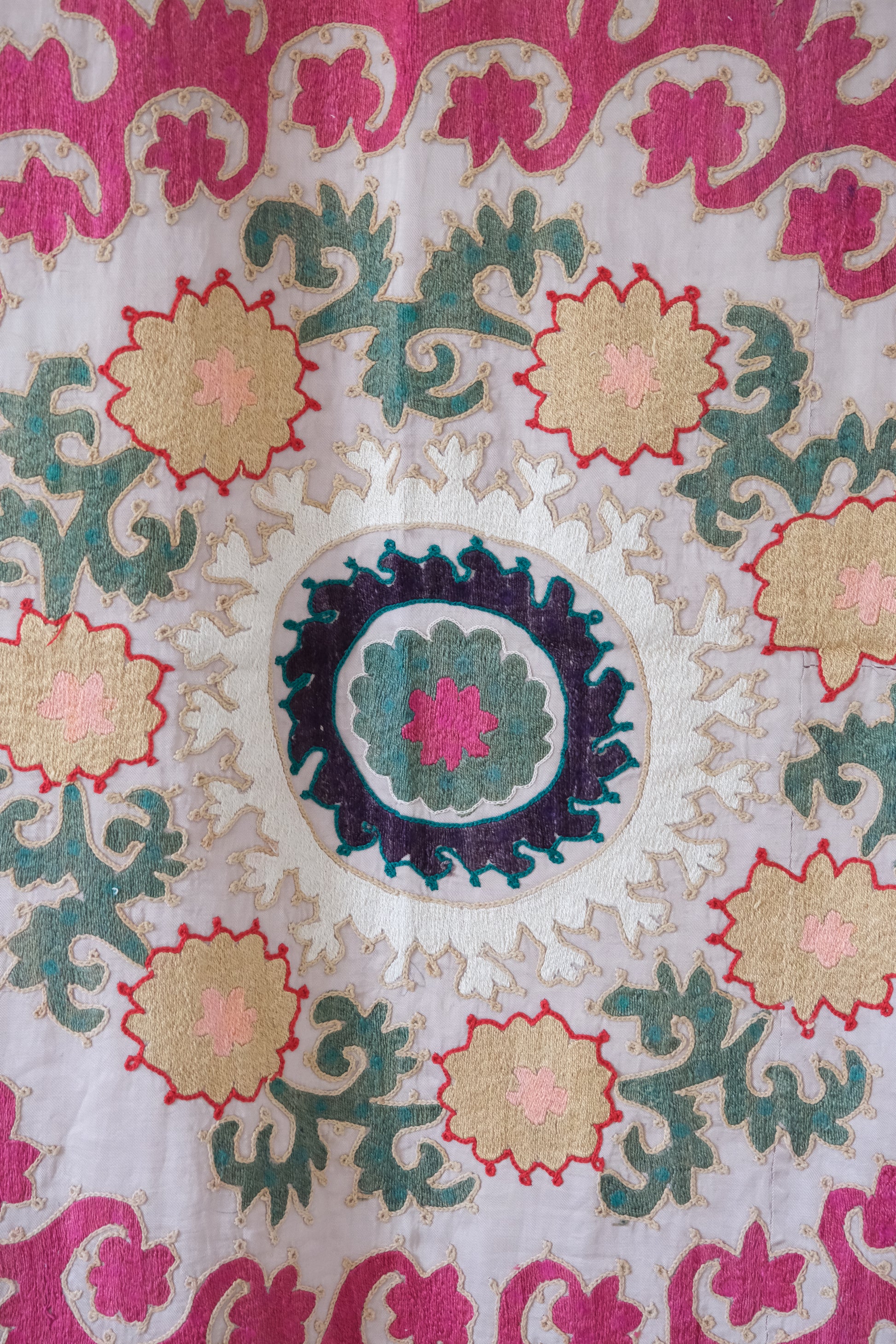 Vintage suzani, decorative embroidered tapestry, pink with geometric and floral design, close-up