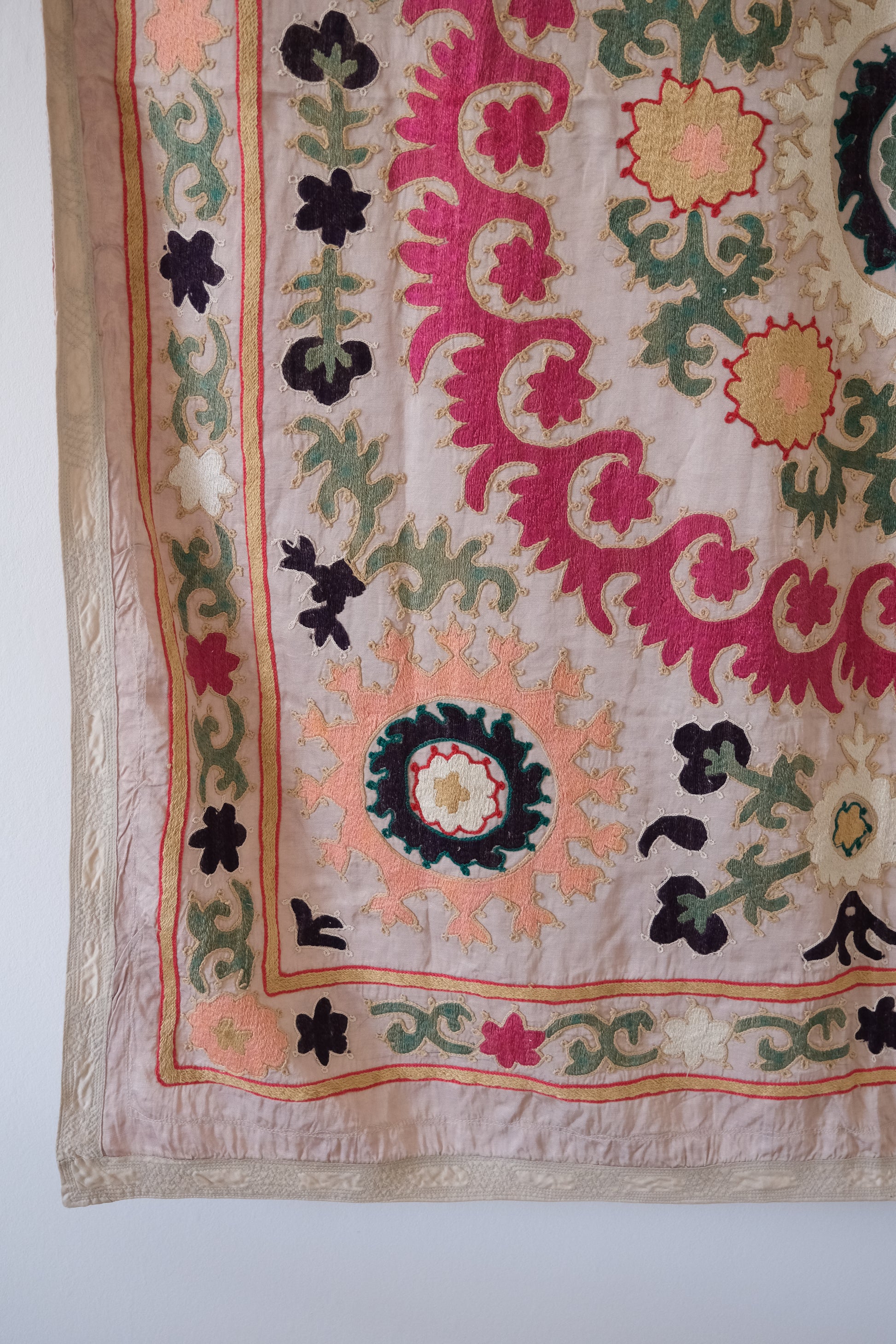 Vintage suzani, decorative embroidered tapestry, pink with geometric and floral design, close-up