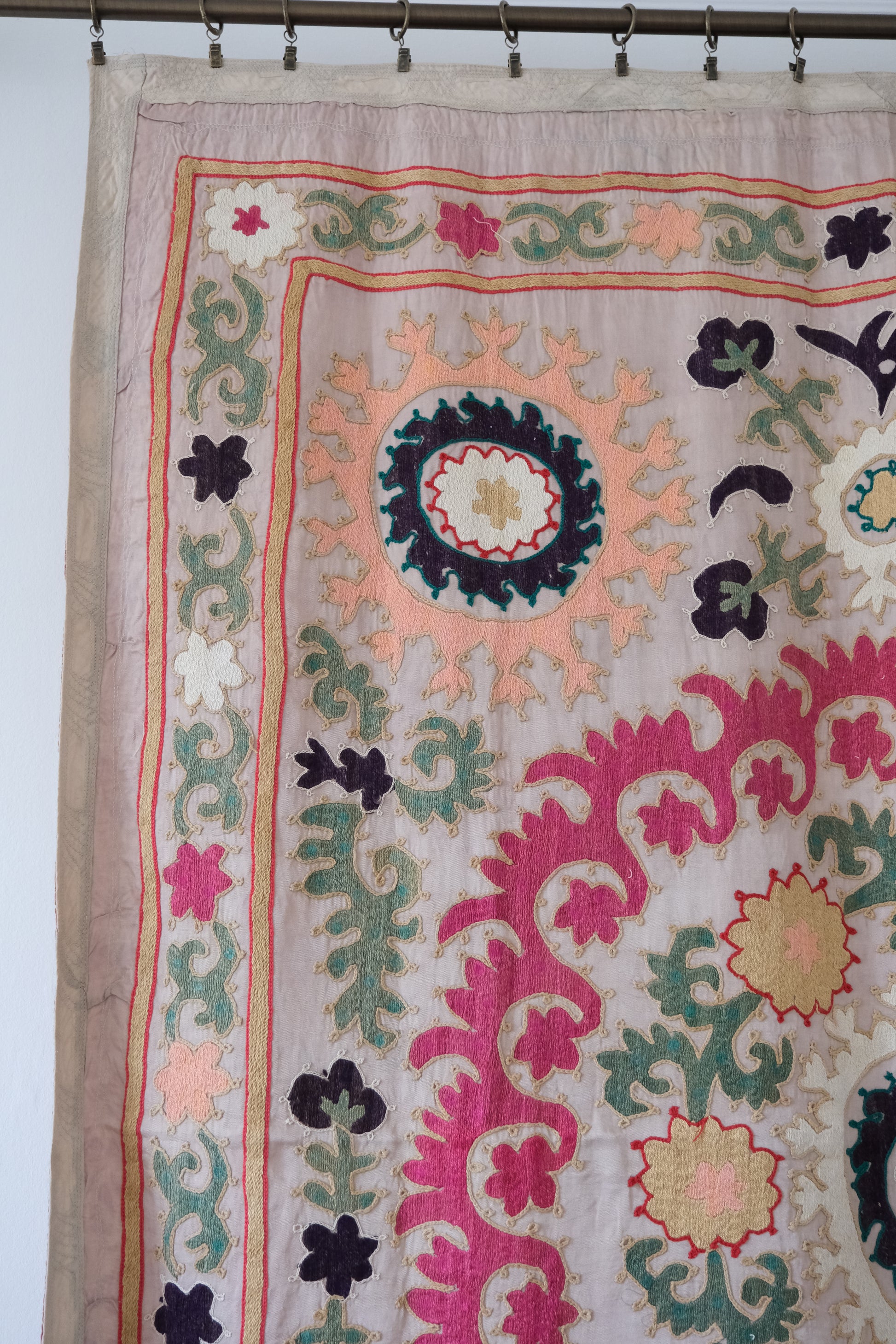 Vintage suzani, decorative embroidered tapestry, pink with geometric and floral design, close-up