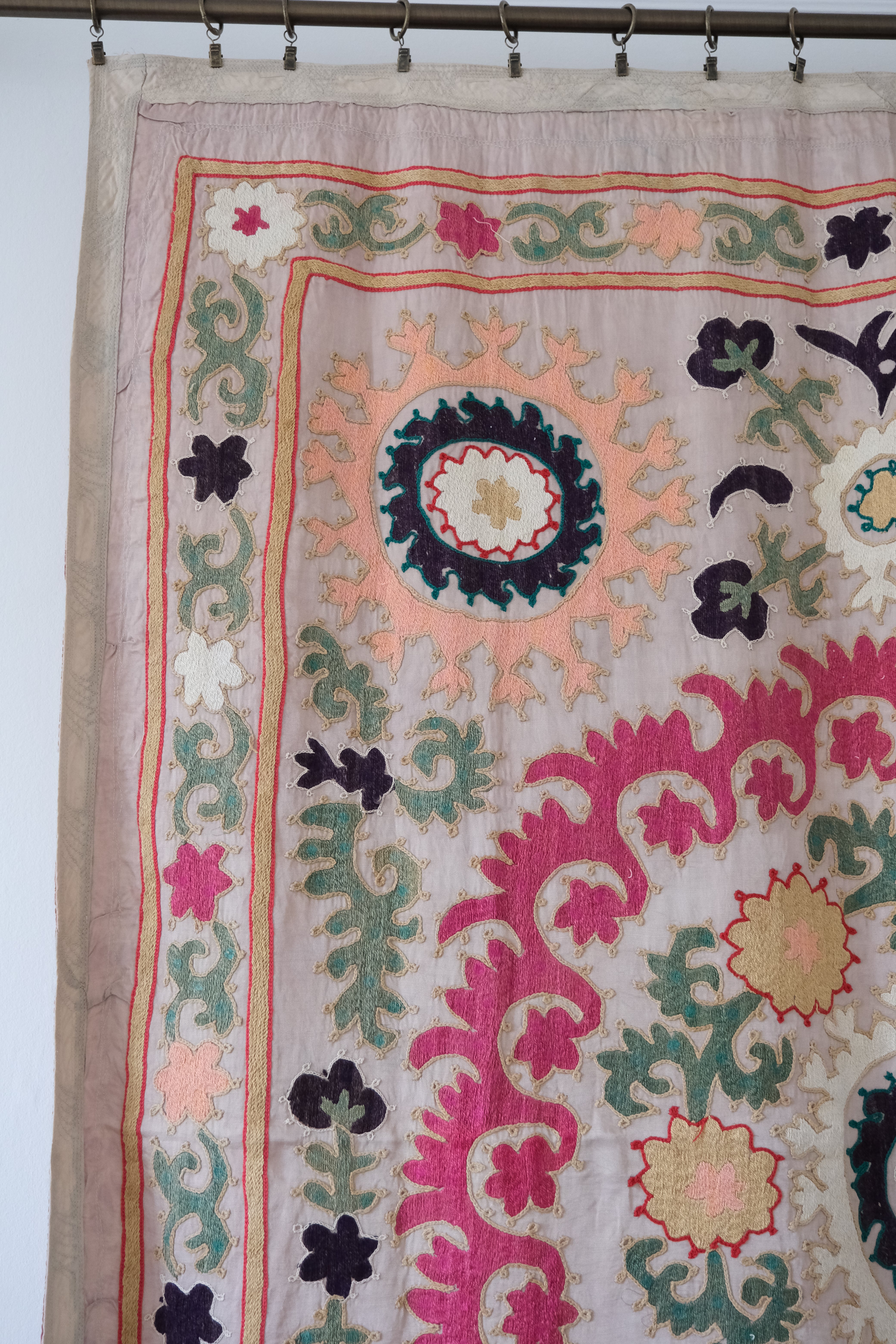 Vintage suzani, decorative embroidered tapestry, pink with geometric and floral design, close-up