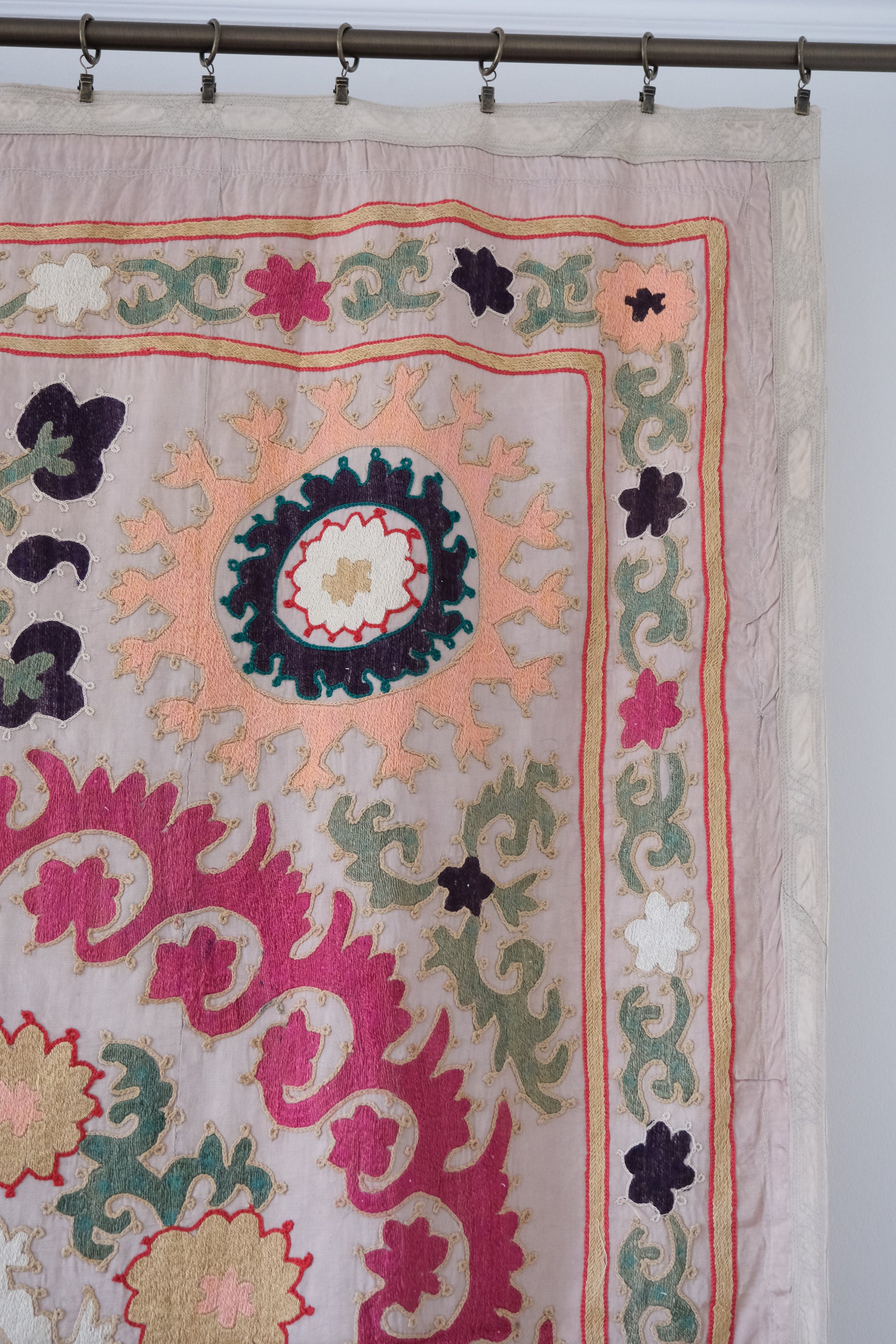 Vintage suzani, decorative embroidered tapestry, pink with geometric and floral design, close-up