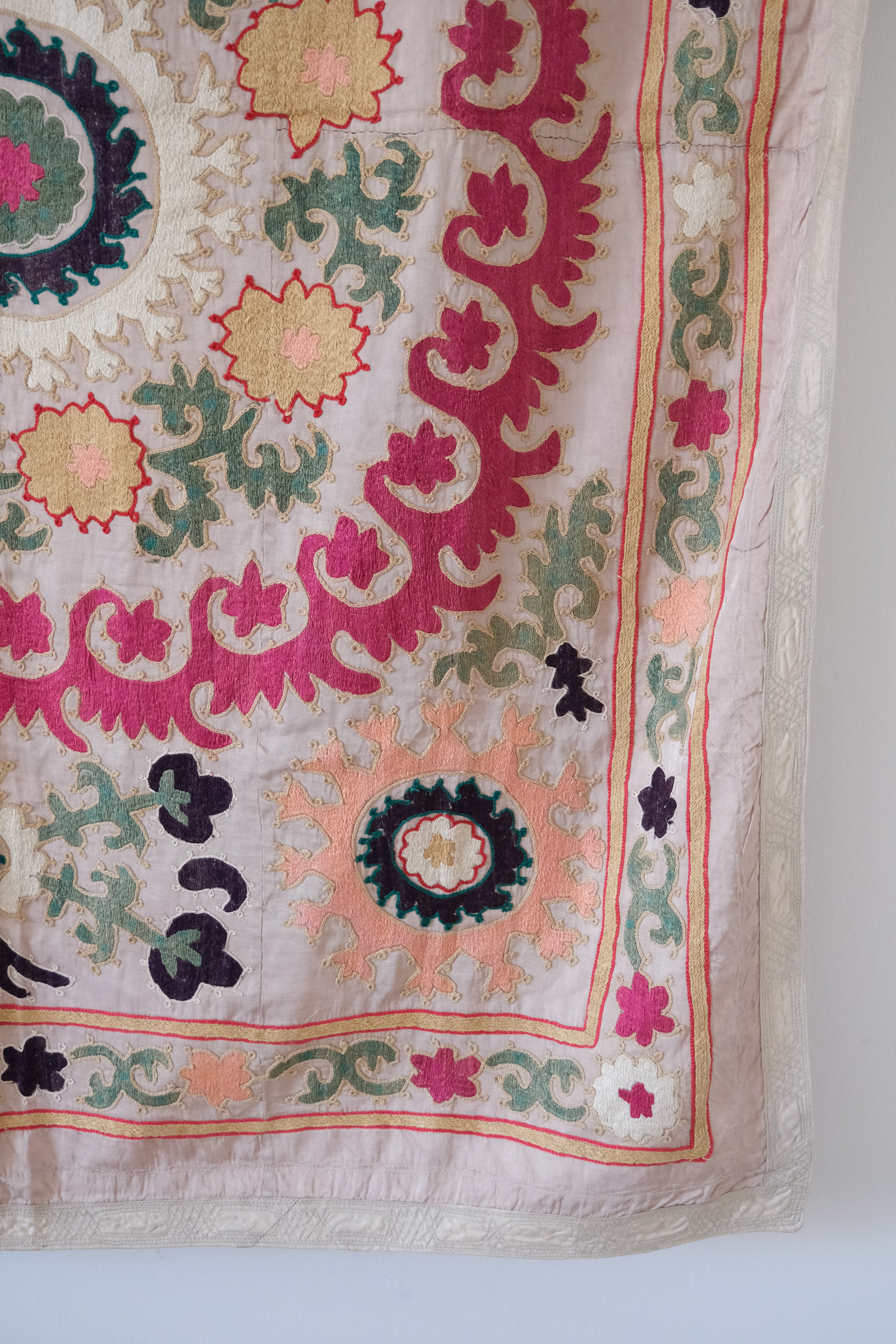 Vintage suzani, decorative embroidered tapestry, pink with geometric and floral design, close-up