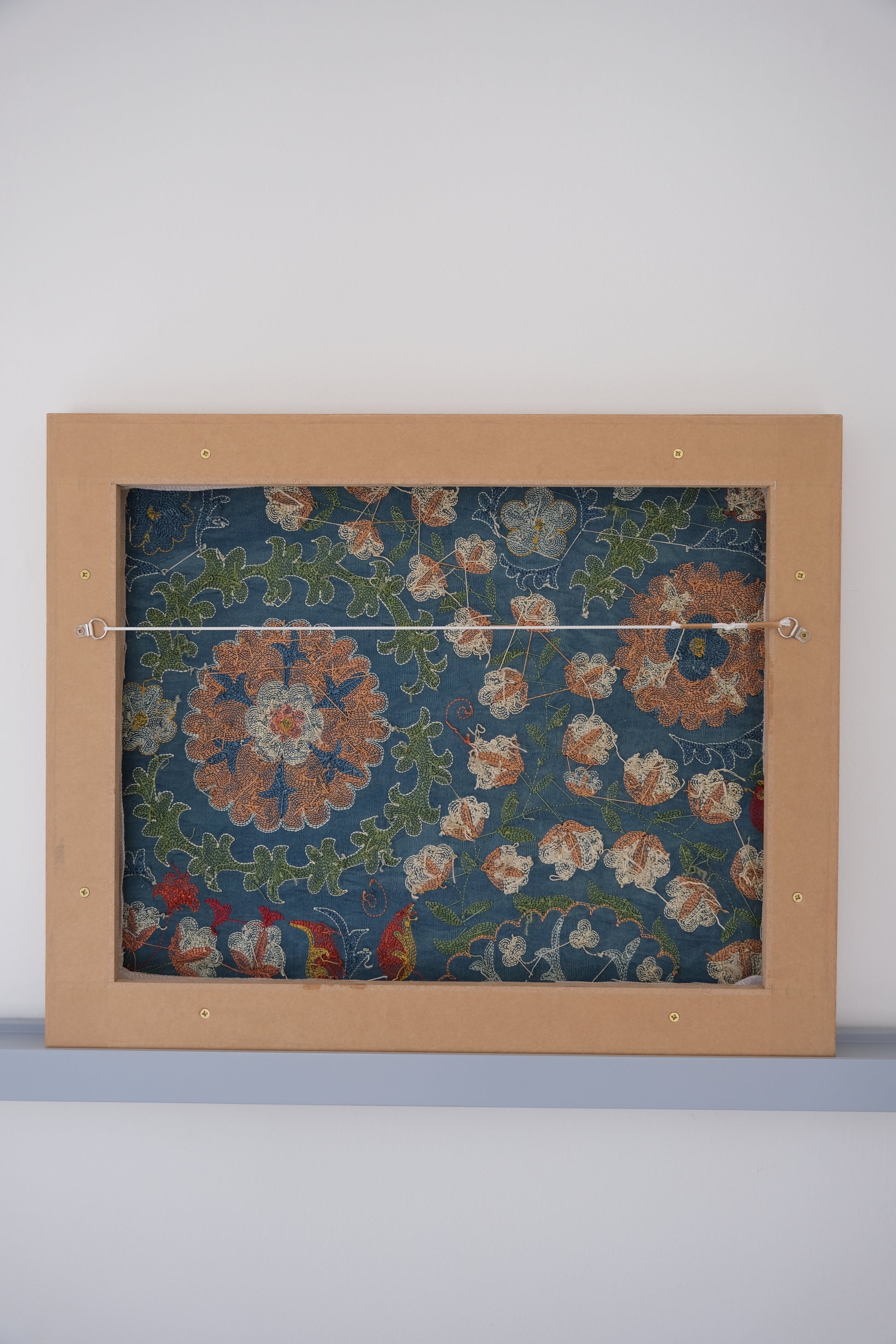 Framed suzani, embroidered textile art, wooden frame, green with orange and blue floral motifs, backside
