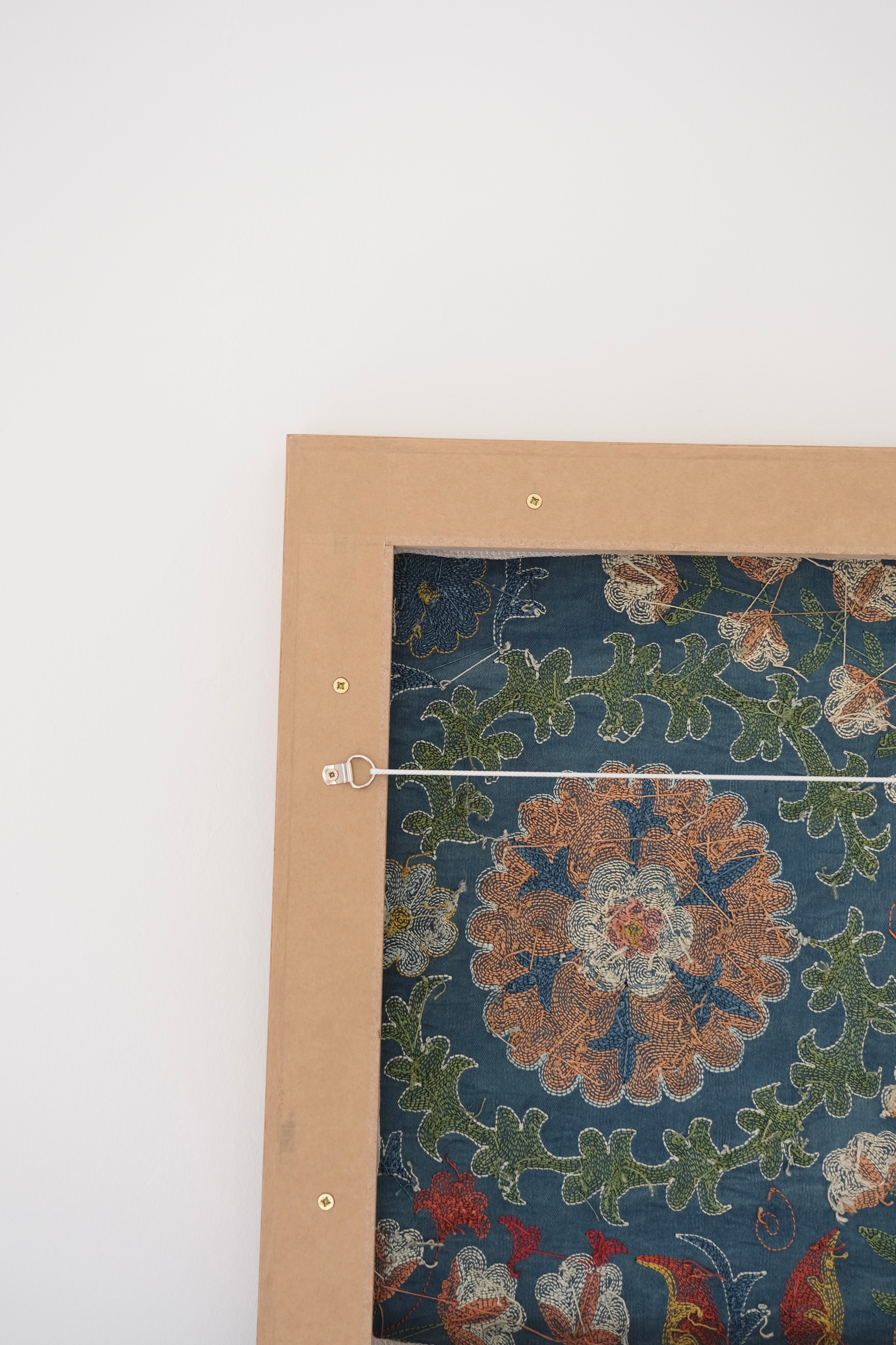 Framed suzani, embroidered textile art, wooden frame, green with orange and blue floral motifs, backside