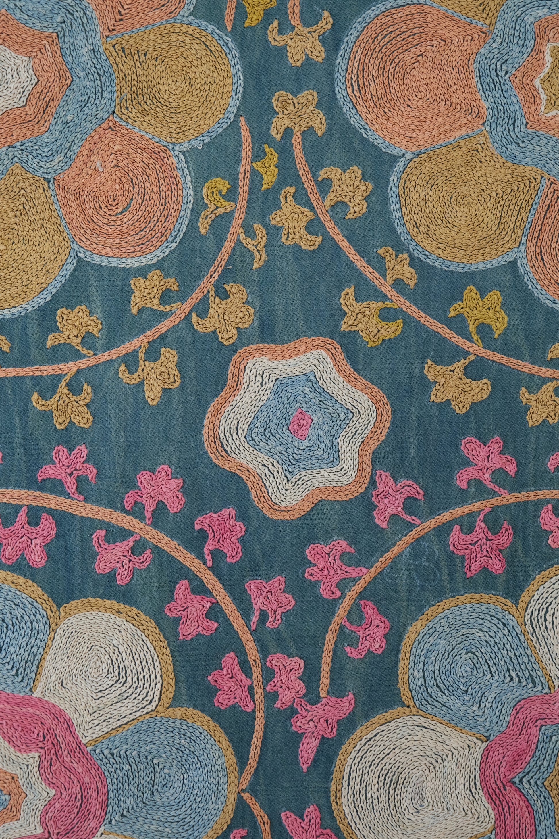 Framed suzani, embroidered textile art, wooden frame, green with orange and pink floral motifs, close-up