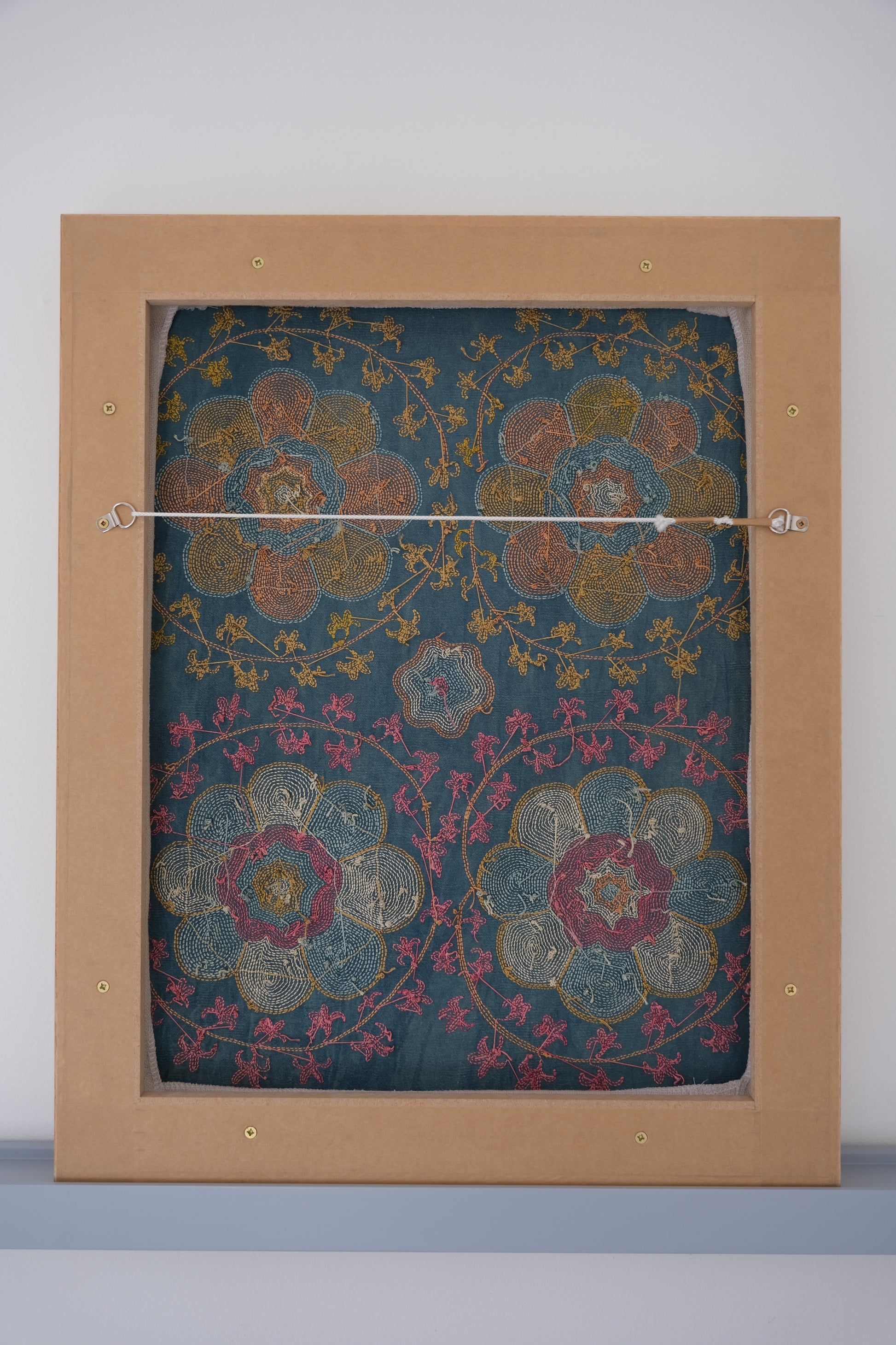 Framed suzani, embroidered textile art, wooden frame, green with orange and pink floral motifs, backside