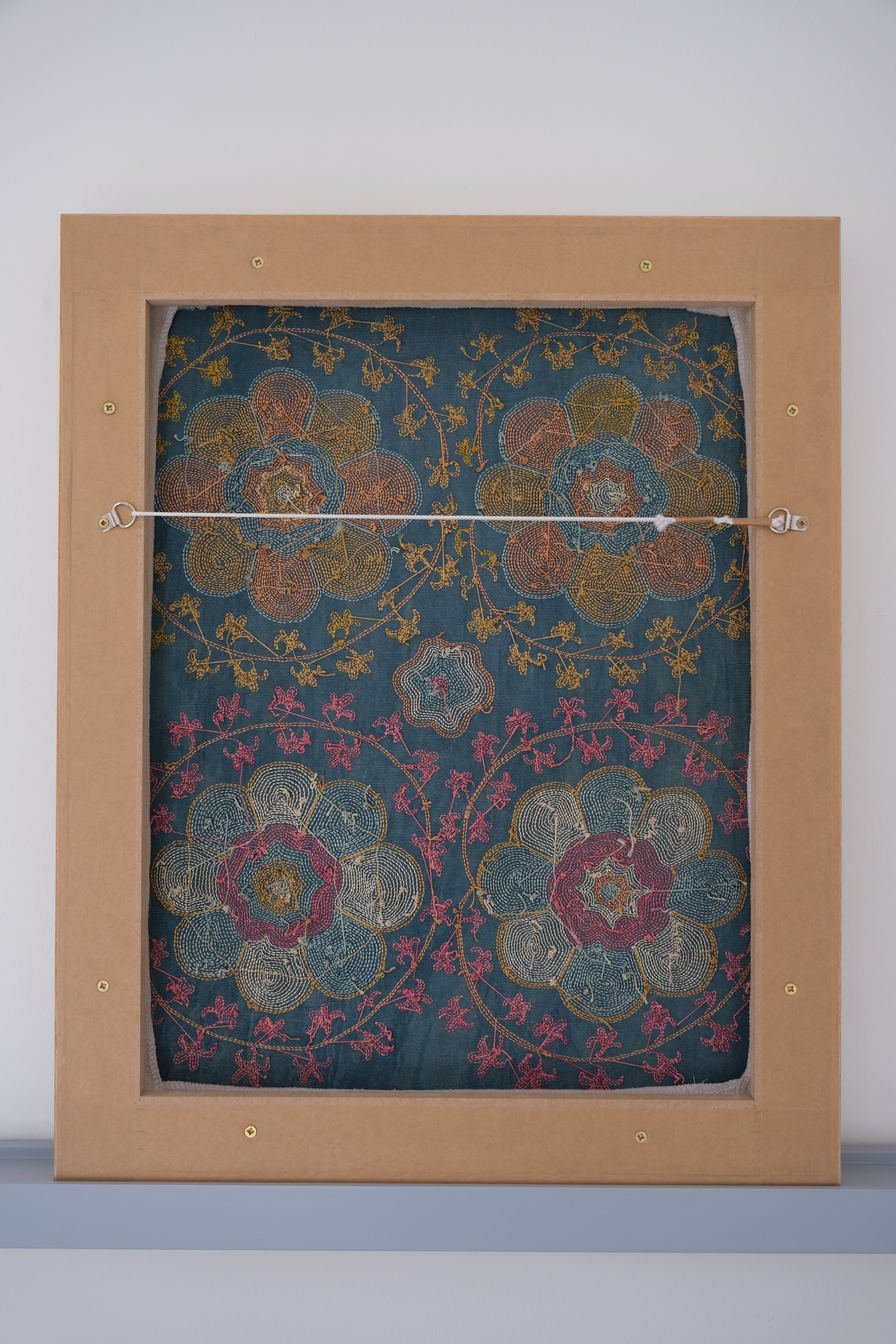 Framed suzani, embroidered textile art, wooden frame, green with orange and pink floral motifs, backside