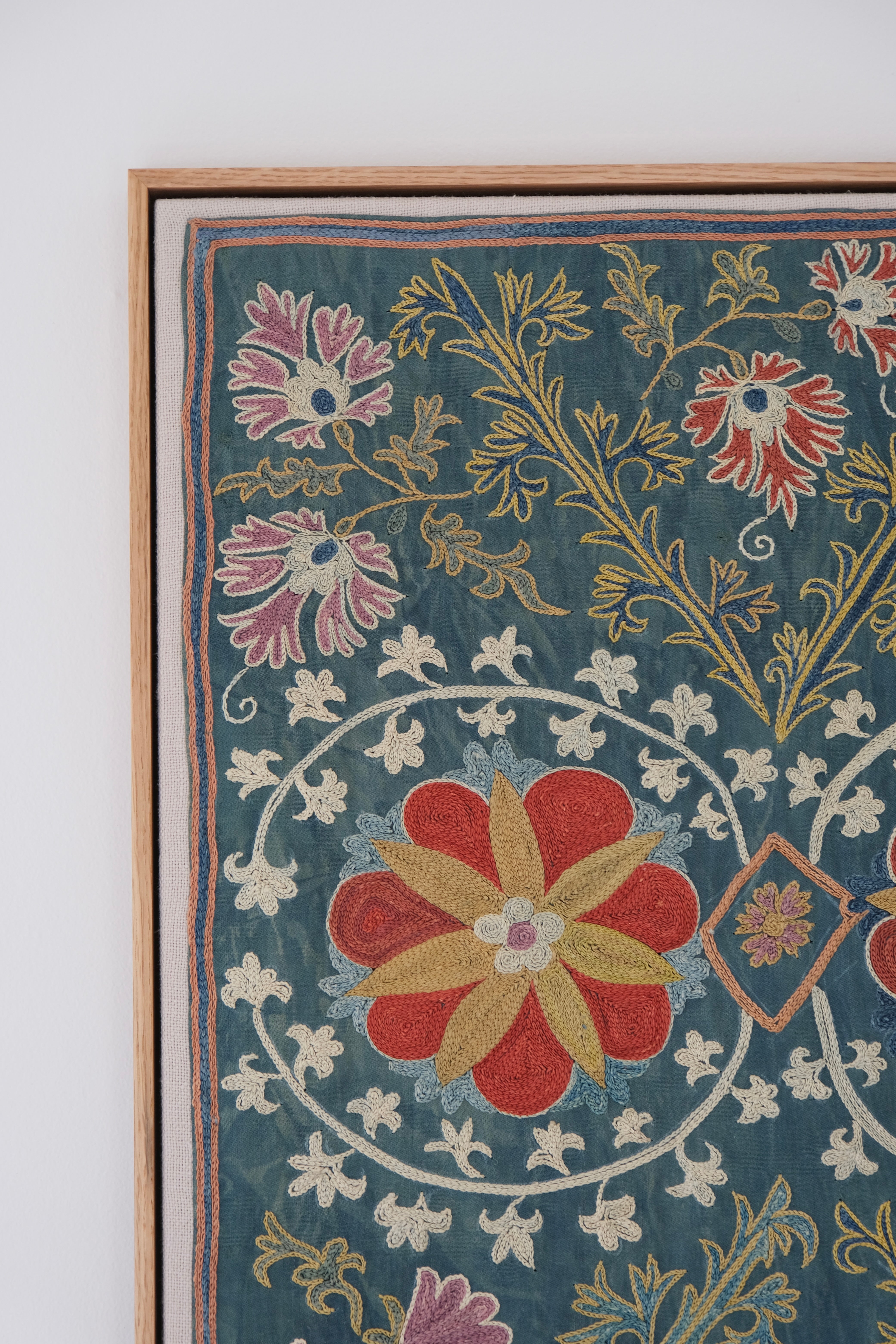Framed suzani, embroidered textile art, wooden frame, green with floral motifs, close-up