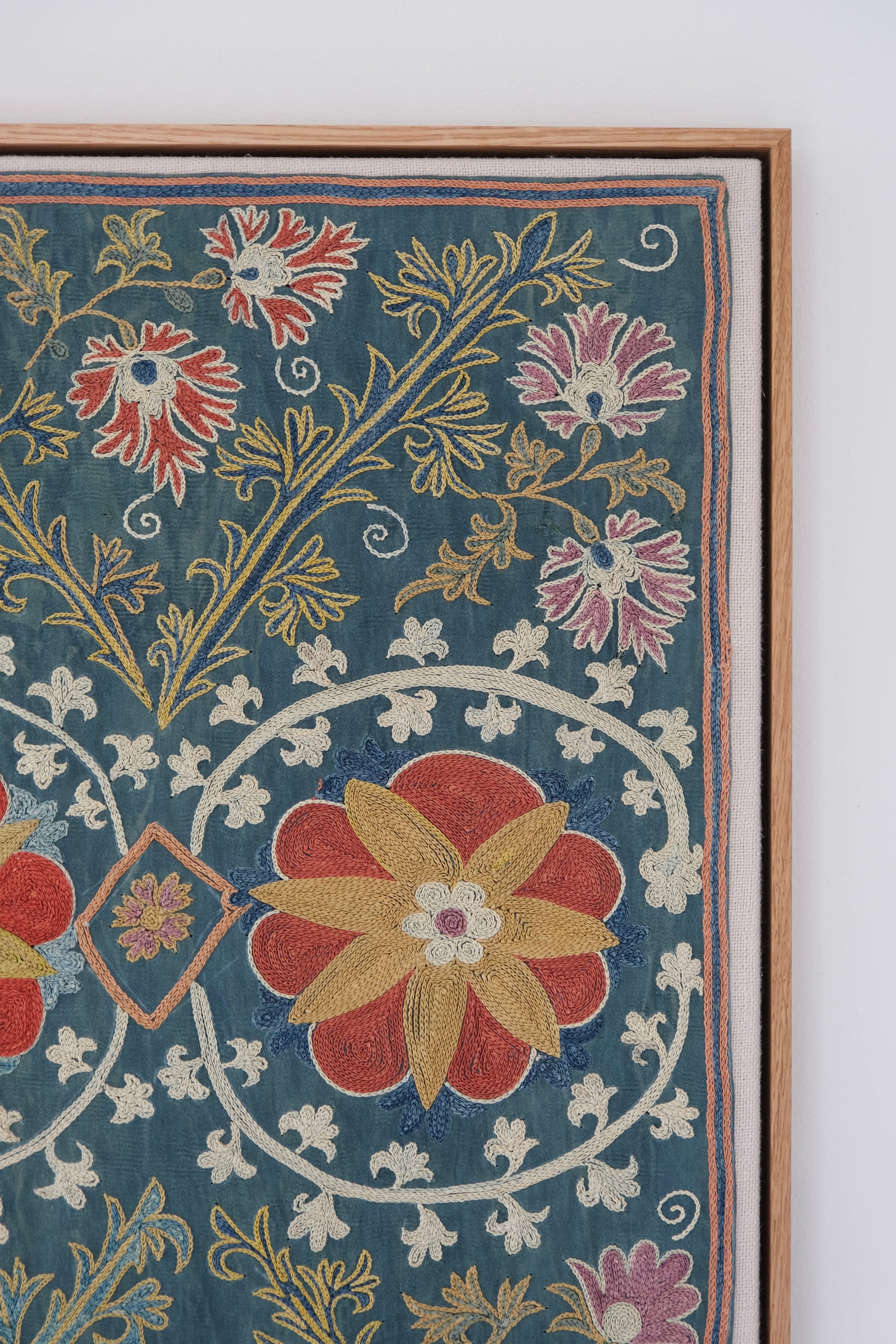 Framed suzani, embroidered textile art, wooden frame, green with floral motifs, close-up