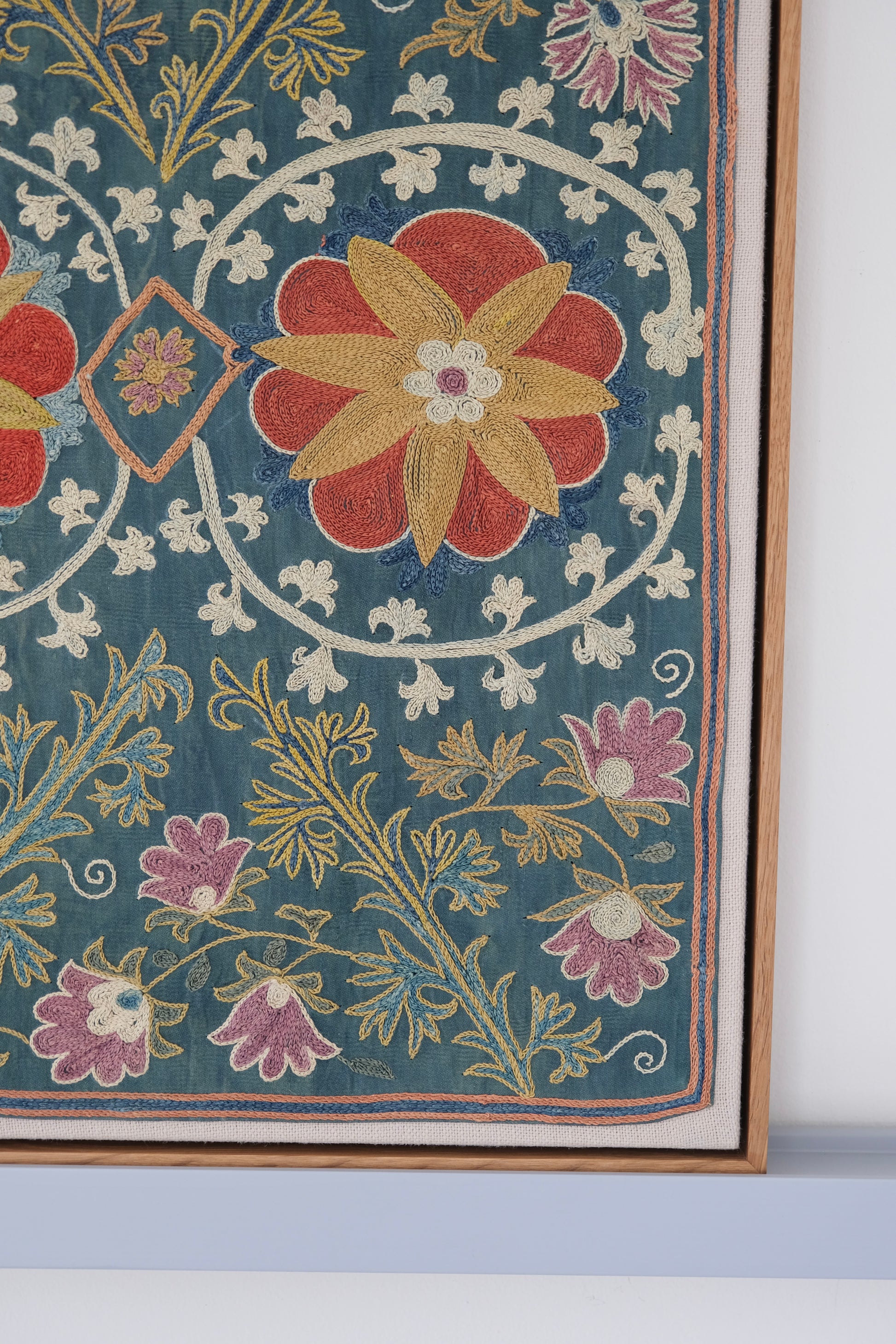Framed suzani, embroidered textile art, wooden frame, green with floral motifs, close-up