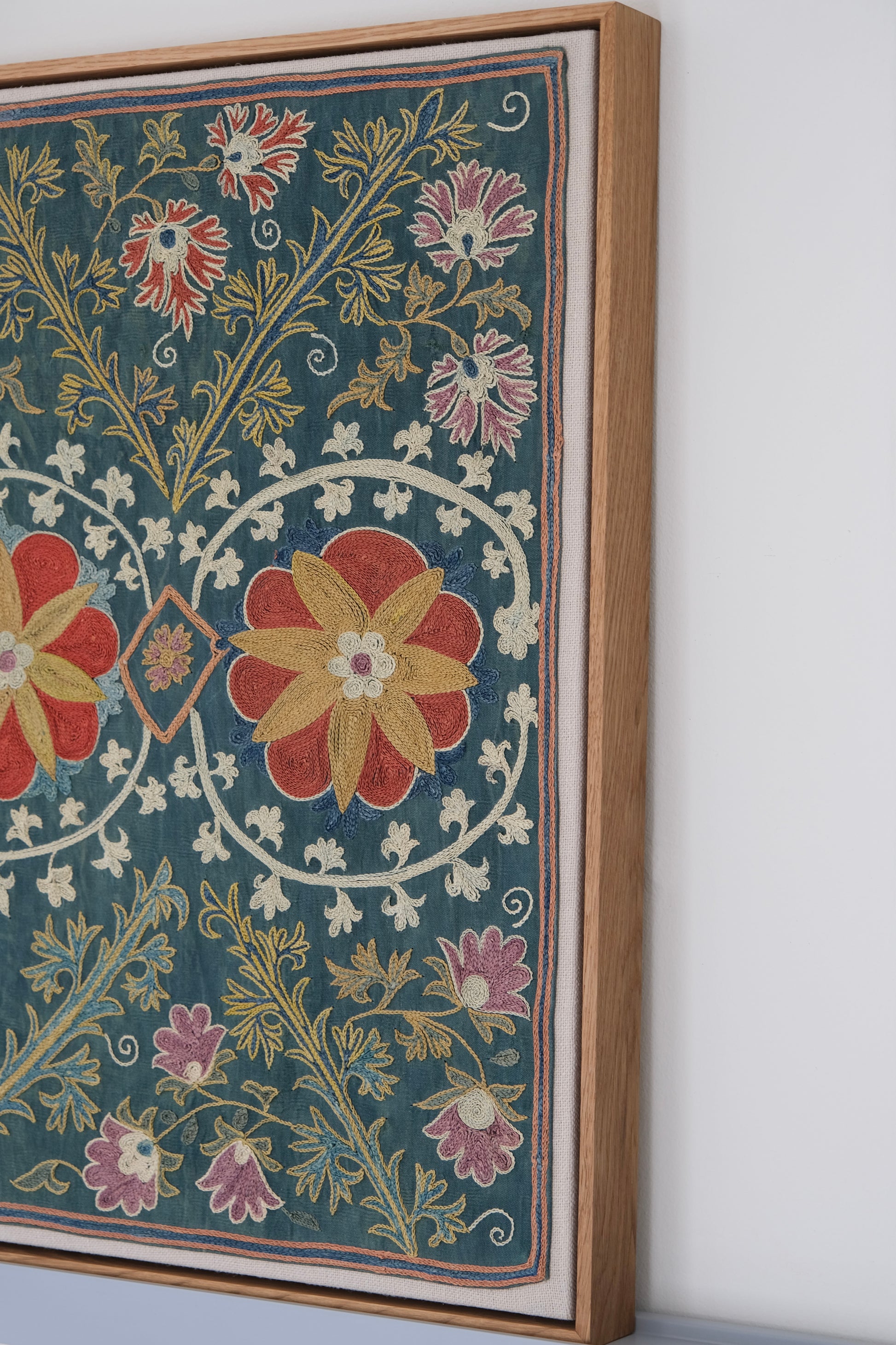 Framed suzani, embroidered textile art, wooden frame, green with floral motifs, side view