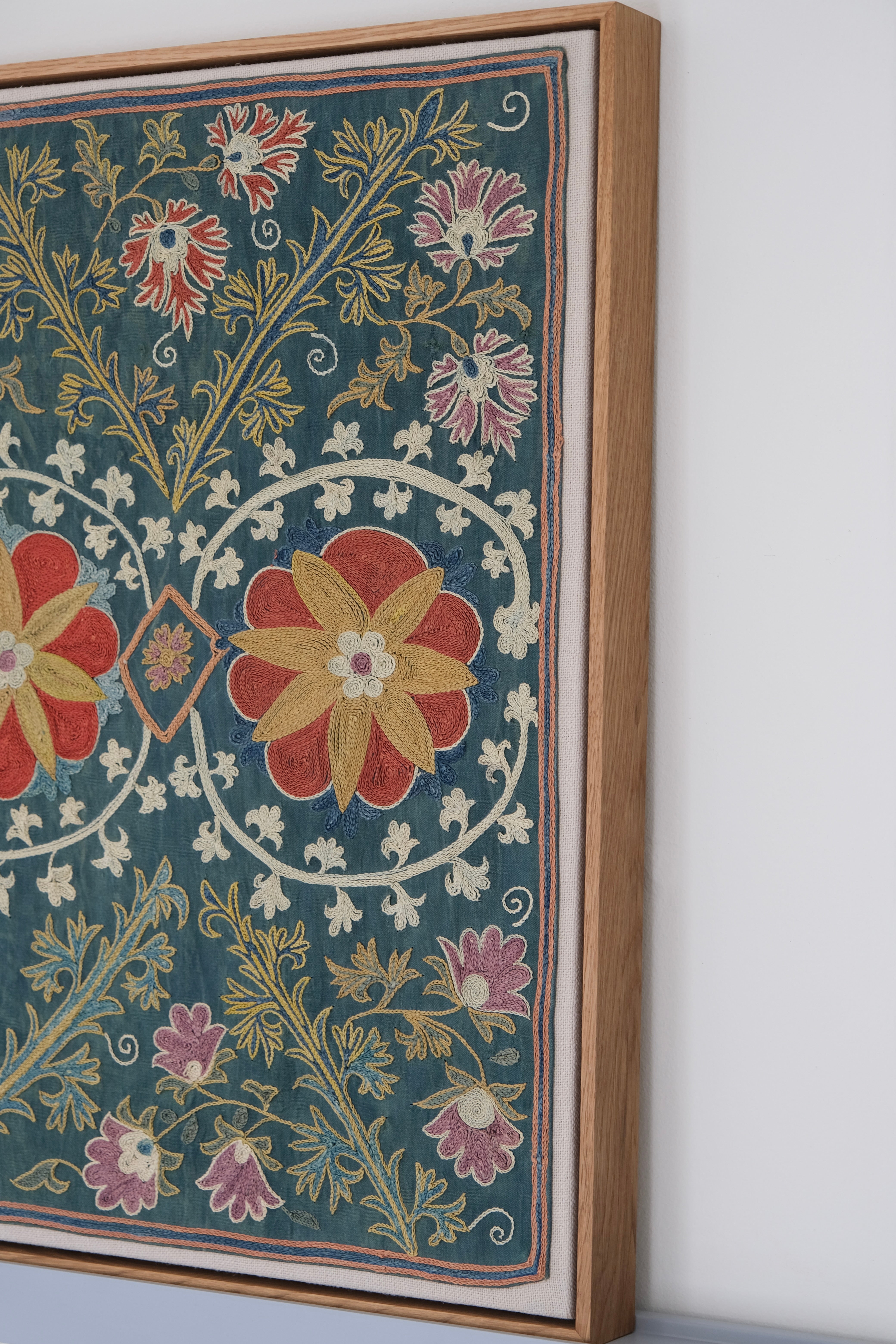 Framed suzani, embroidered textile art, wooden frame, green with floral motifs, side view