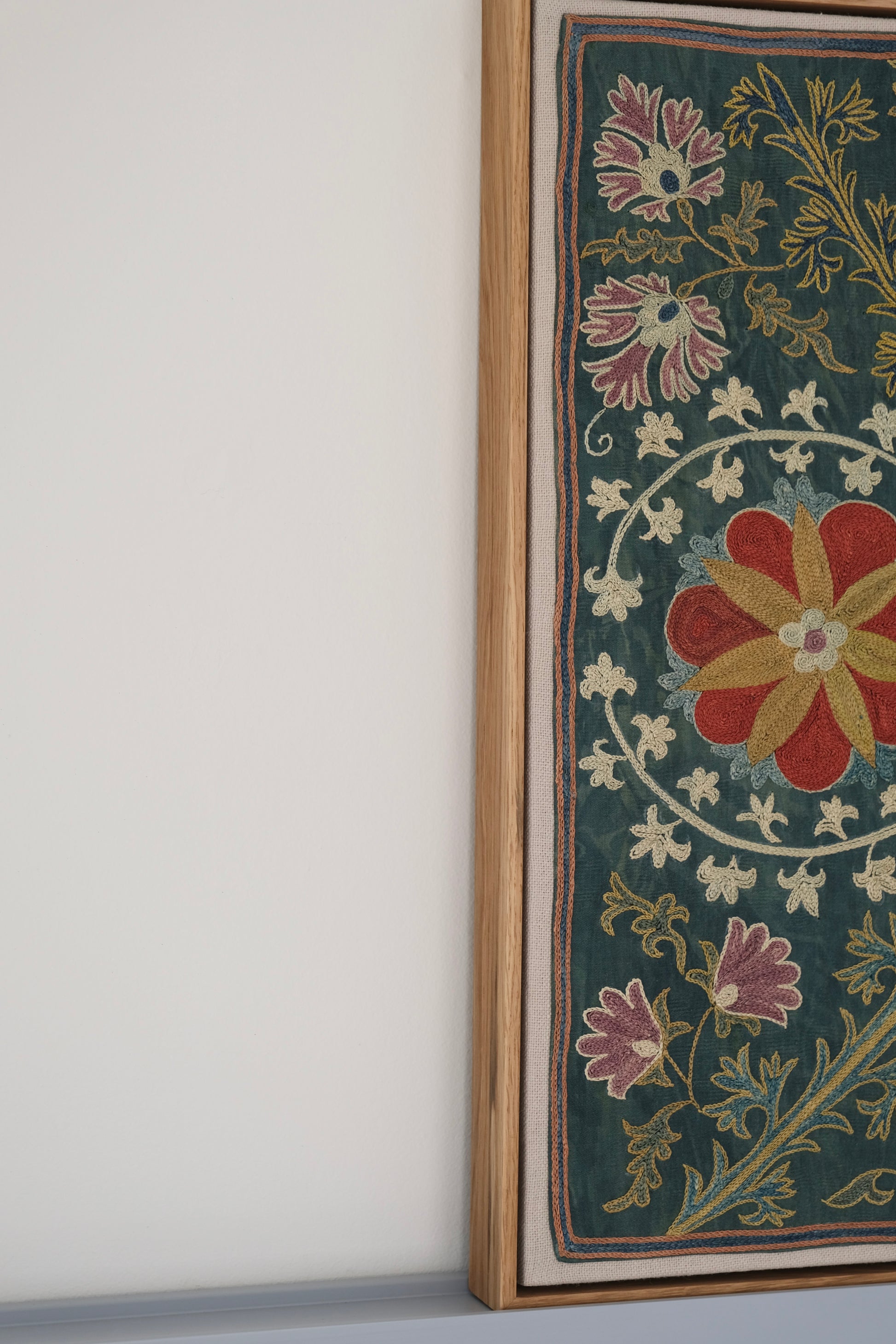 Framed suzani, embroidered textile art, wooden frame, green with floral motifs, side view