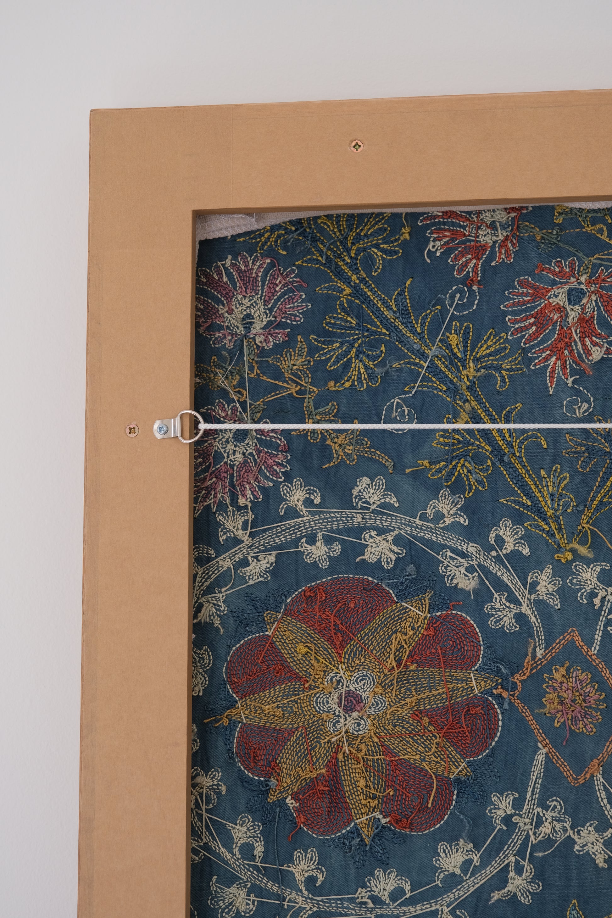 Framed suzani, embroidered textile art, wooden frame, green with floral motifs, side view