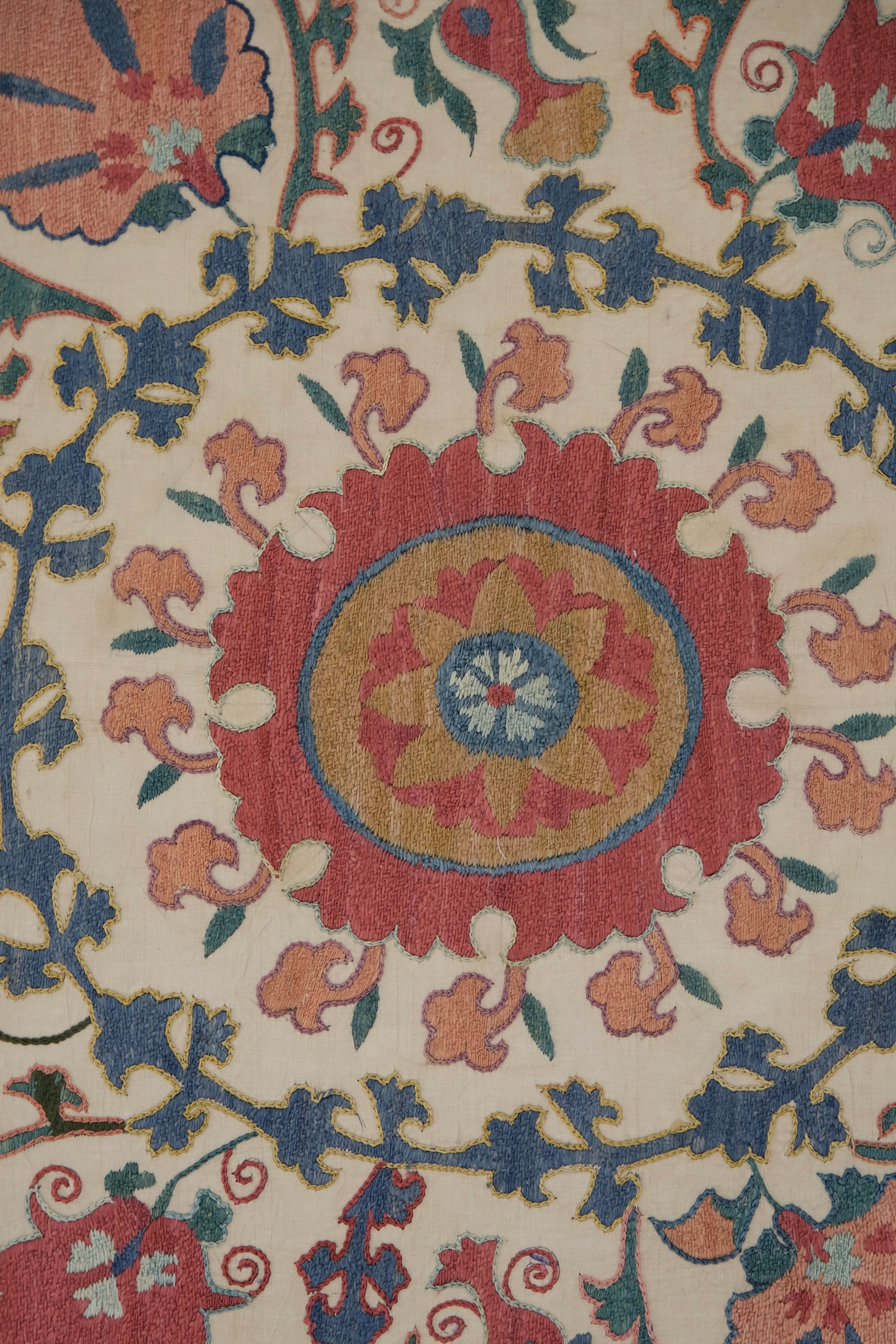 Framed suzani, embroidered textile art, wooden frame, white with pink and blue design, close-up