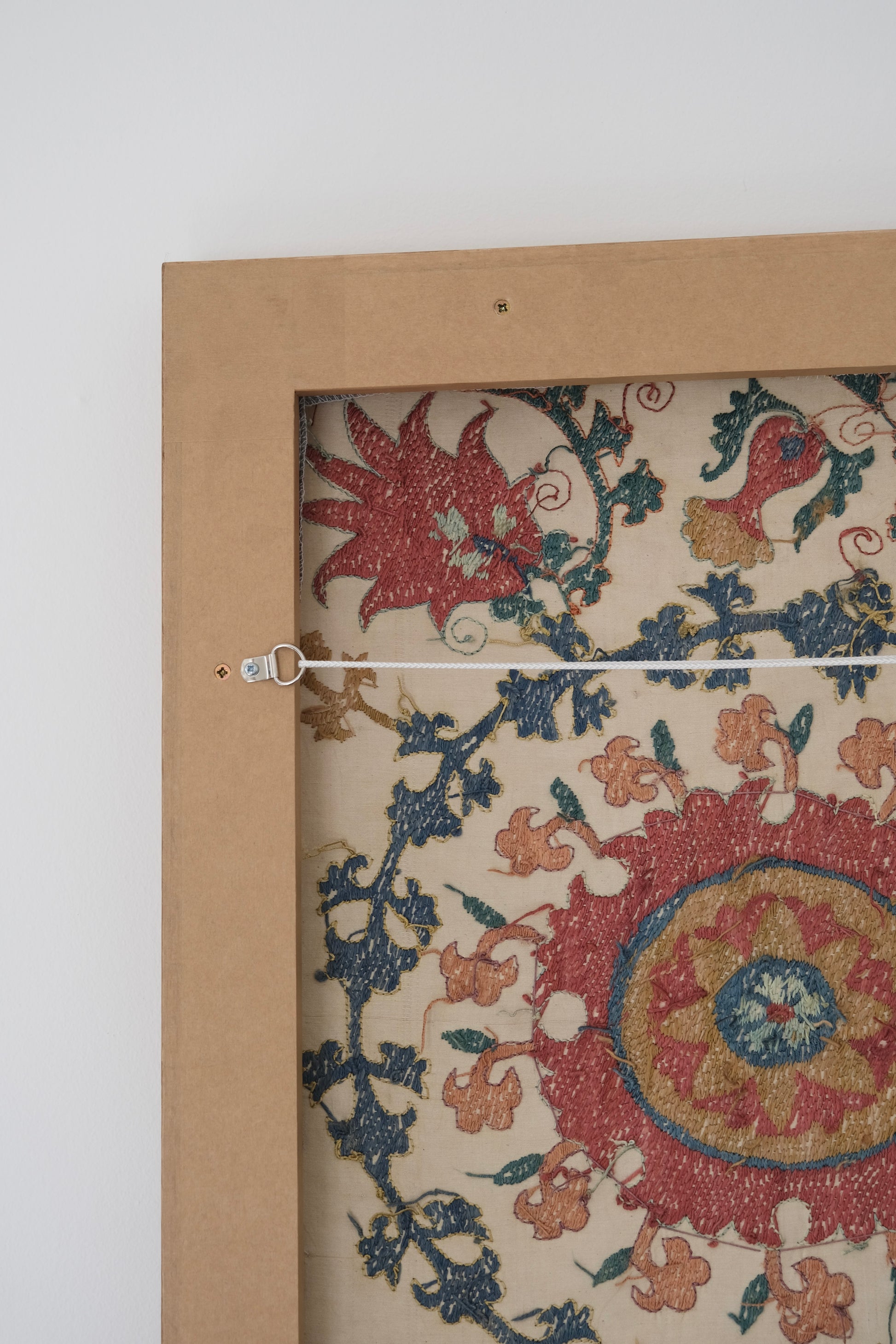 Framed suzani, embroidered textile art, wooden frame, white with pink and blue design, backside