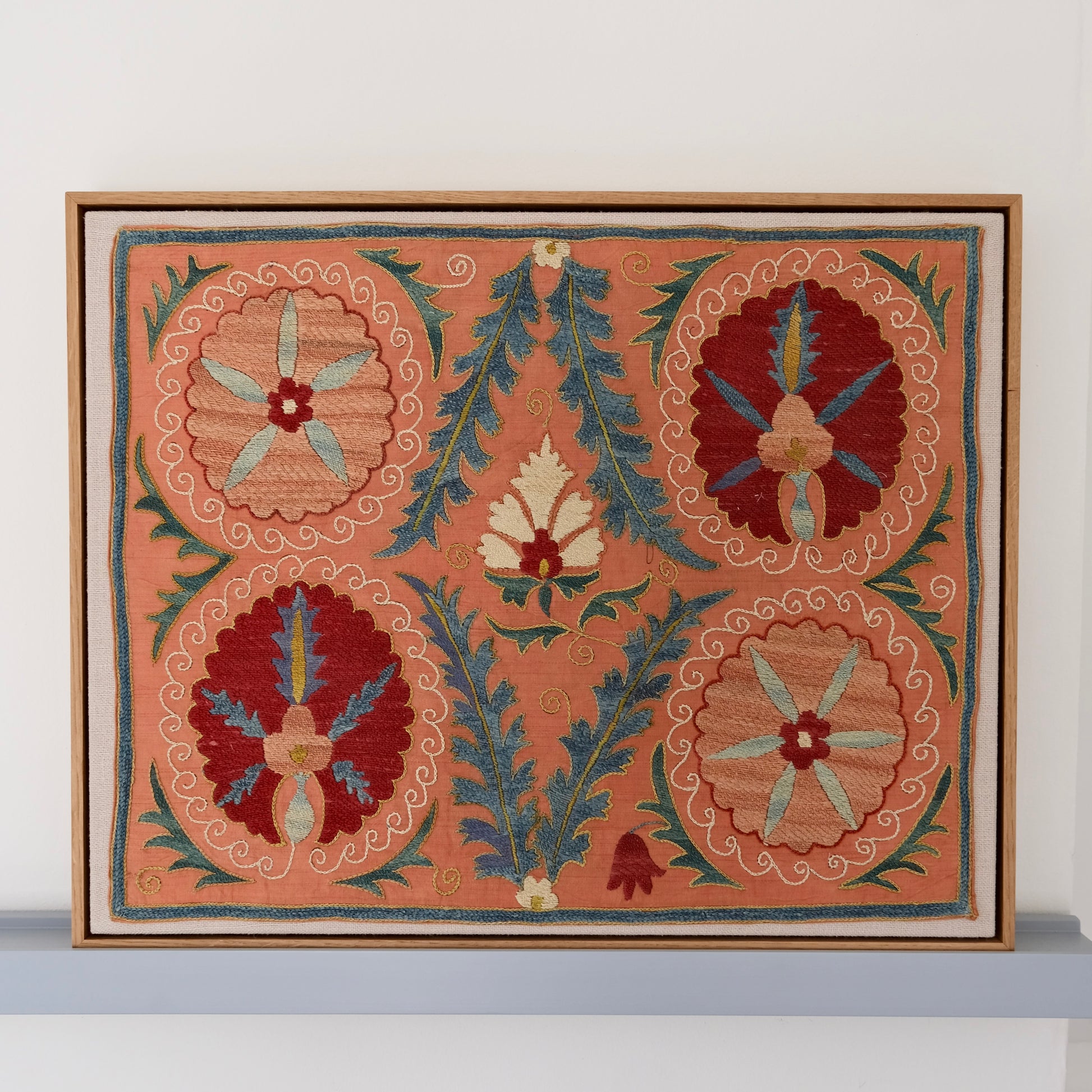 Framed suzani, embroidered textile art, wooden frame, light orange with red and blue floral motifs