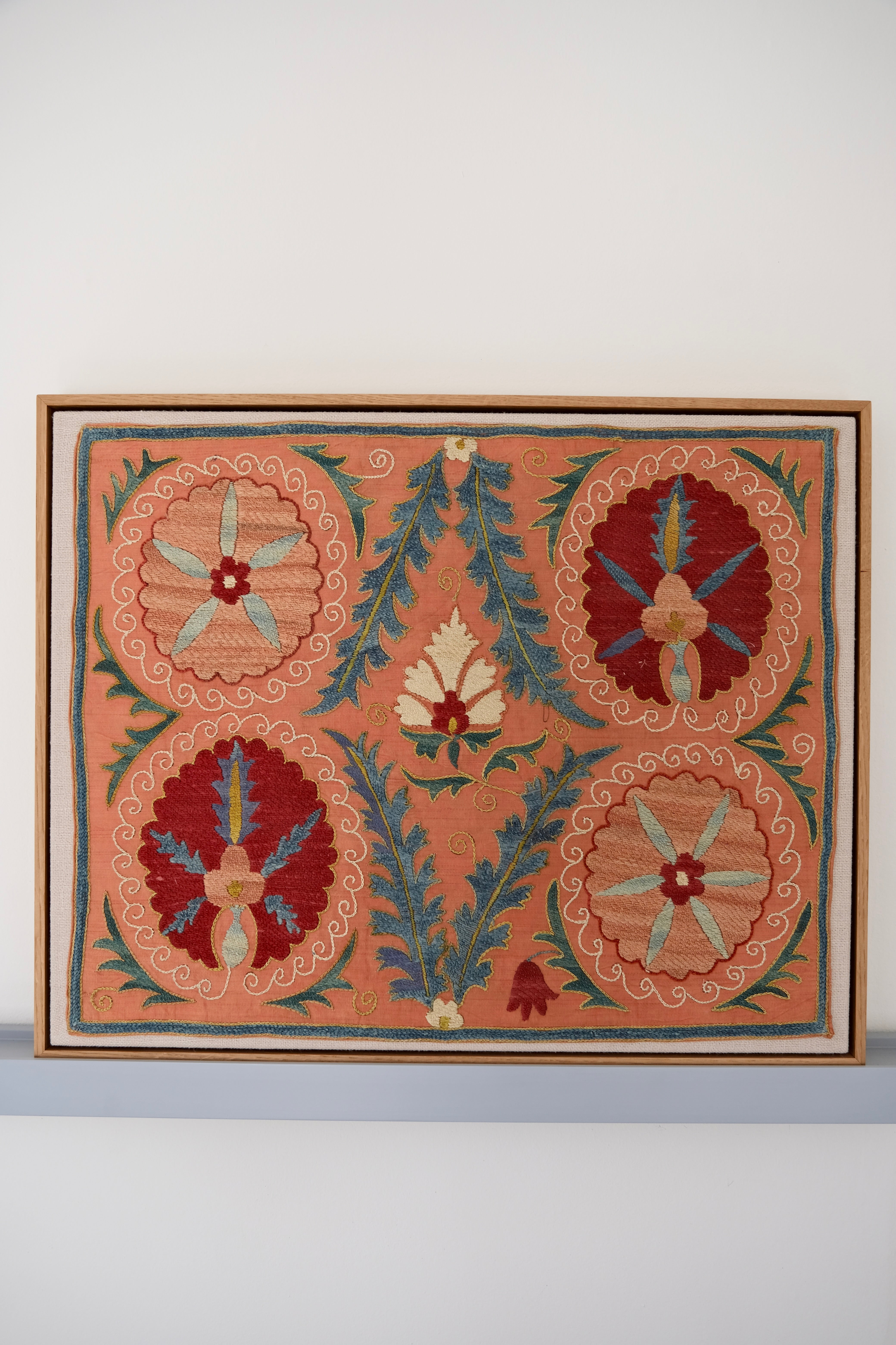 Framed suzani, embroidered textile art, wooden frame, light orange with red and blue floral motifs