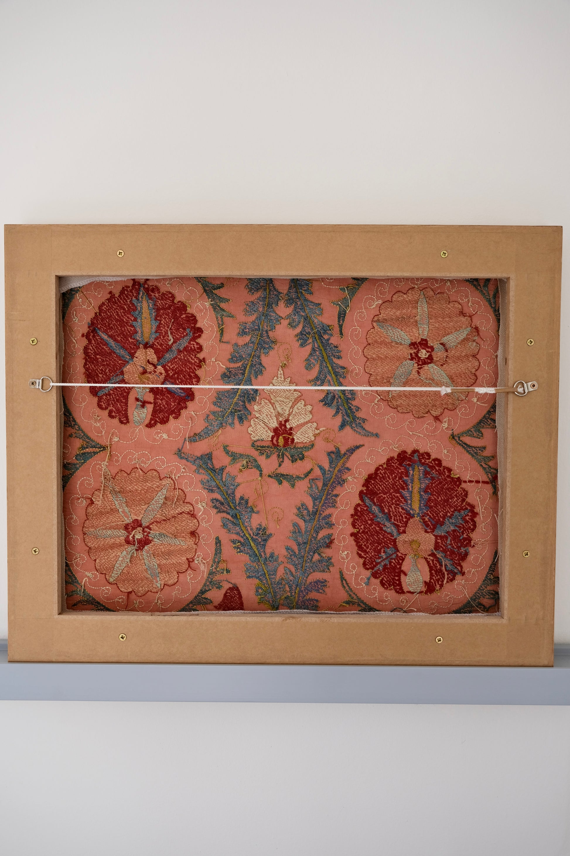 Framed suzani, embroidered textile art, wooden frame, light orange with red and blue floral motifs, backside