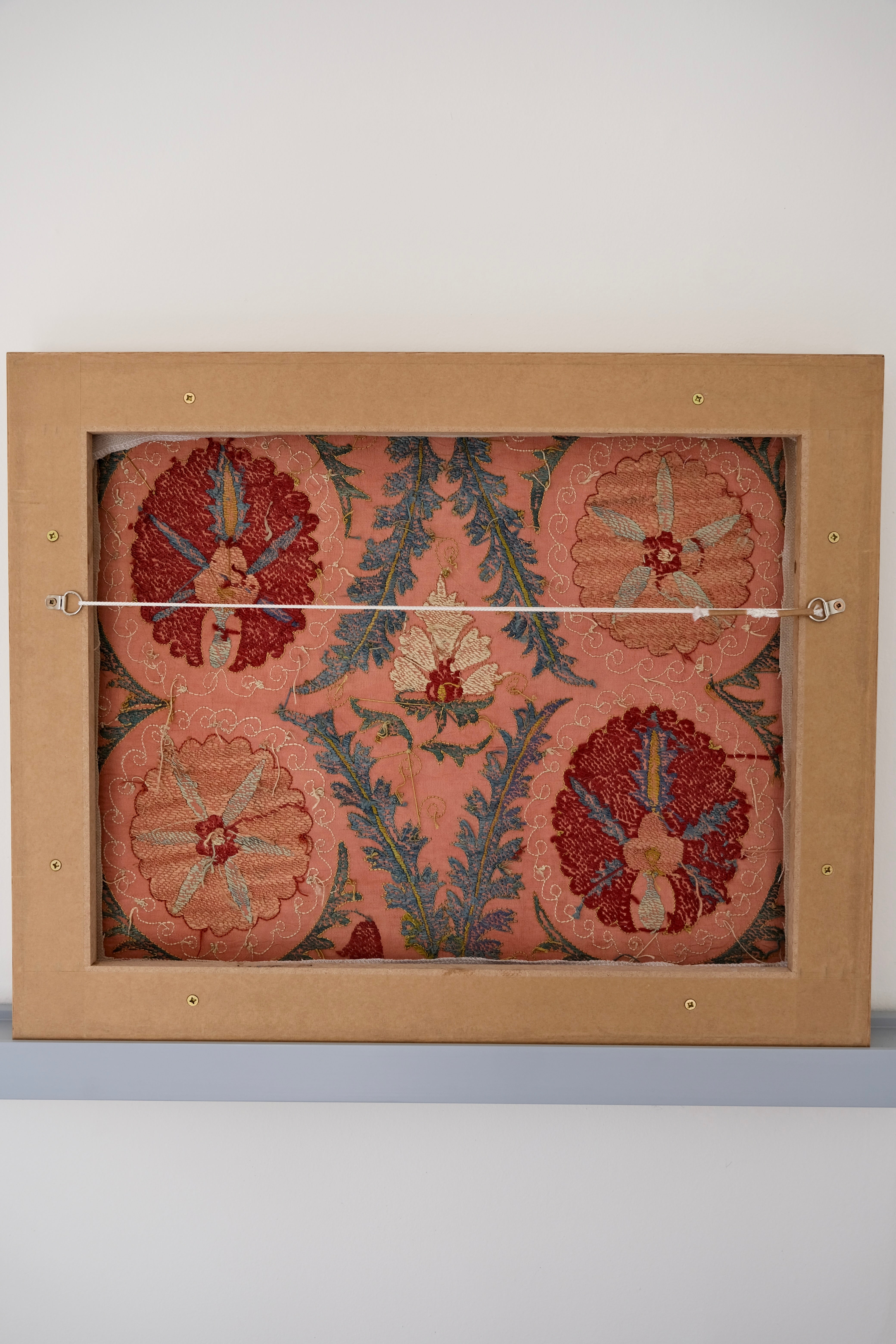 Framed suzani, embroidered textile art, wooden frame, light orange with red and blue floral motifs, backside
