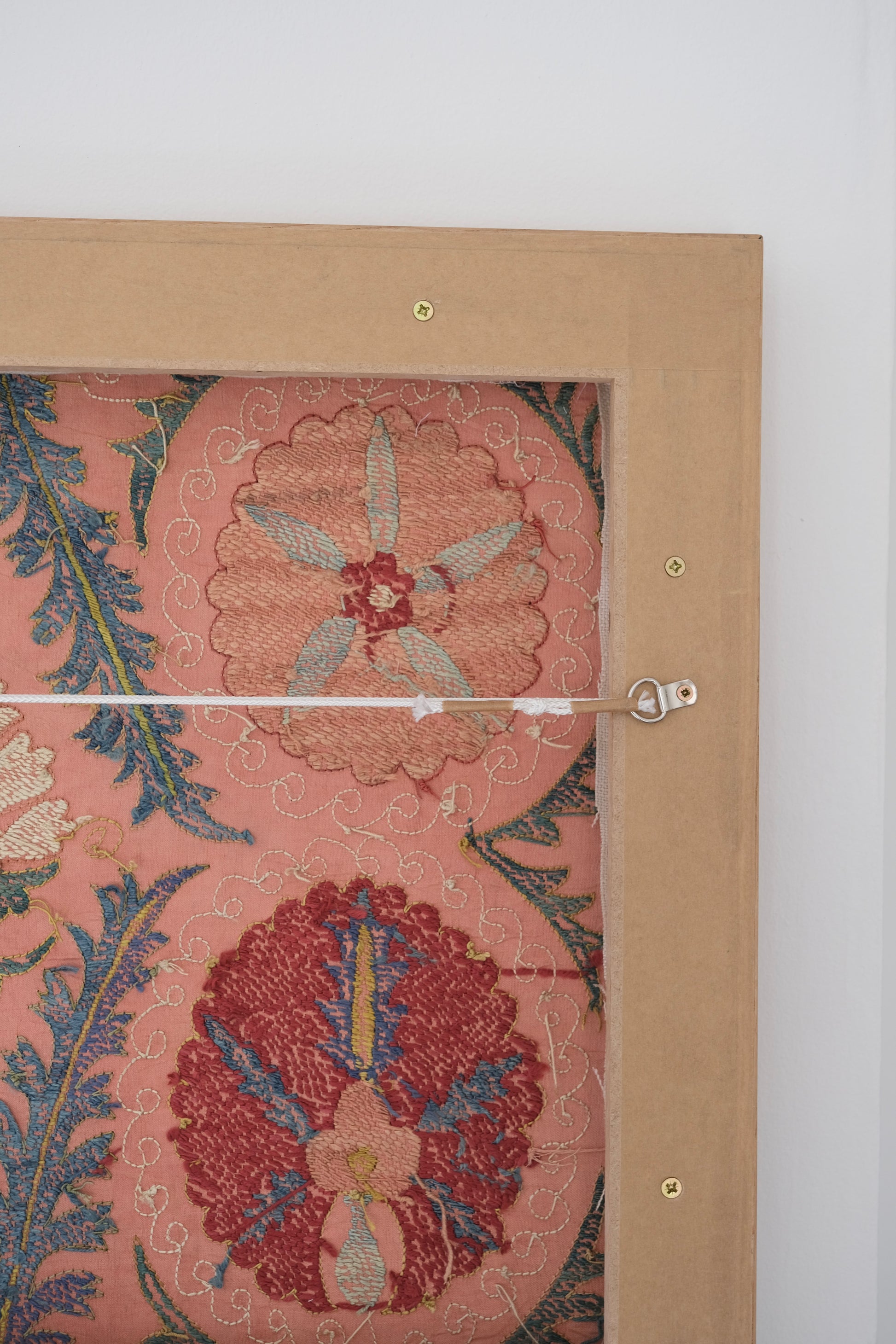 Framed suzani, embroidered textile art, wooden frame, light orange with red and blue floral motifs, backside