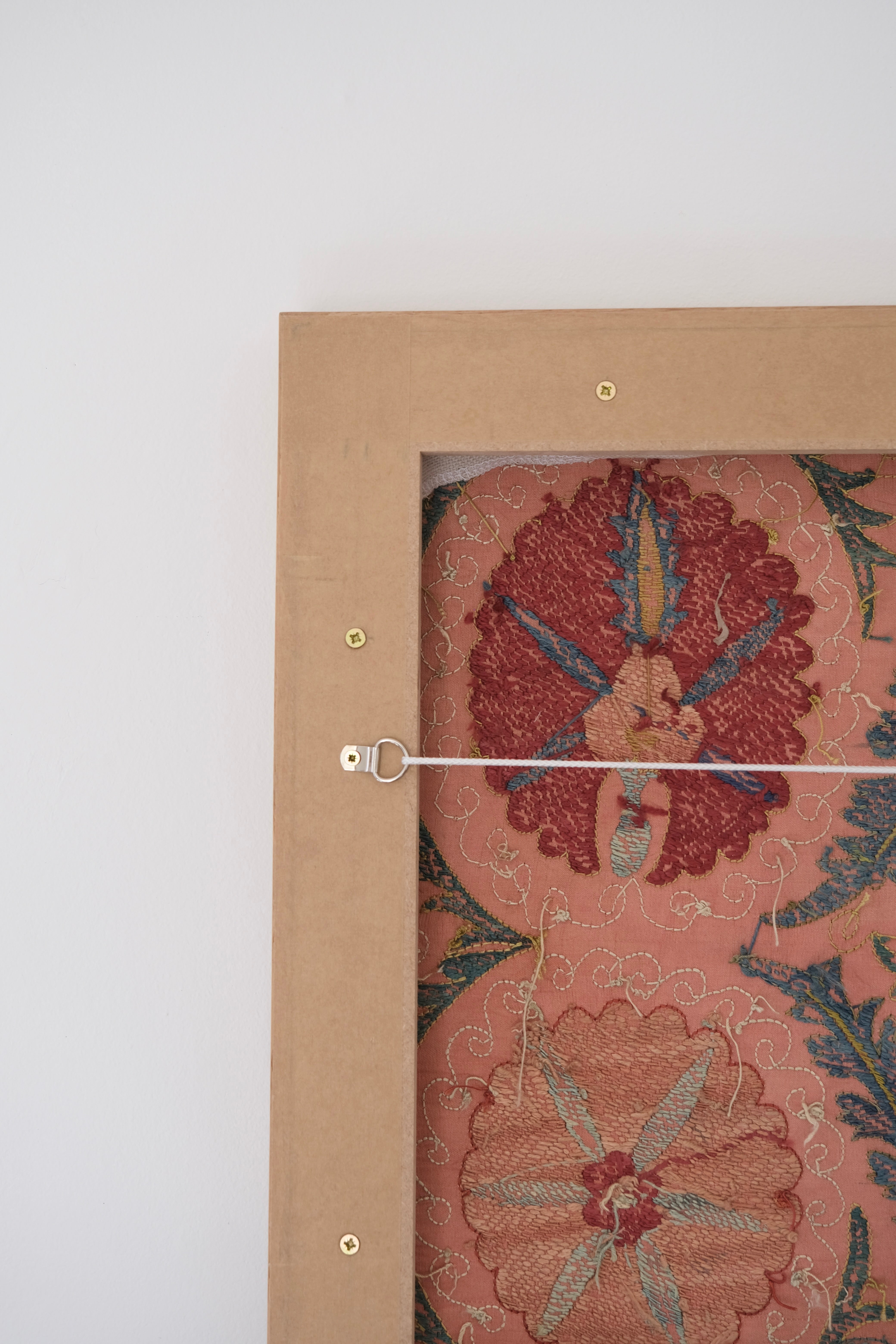 Framed suzani, embroidered textile art, wooden frame, light orange with red and blue floral motifs, backside