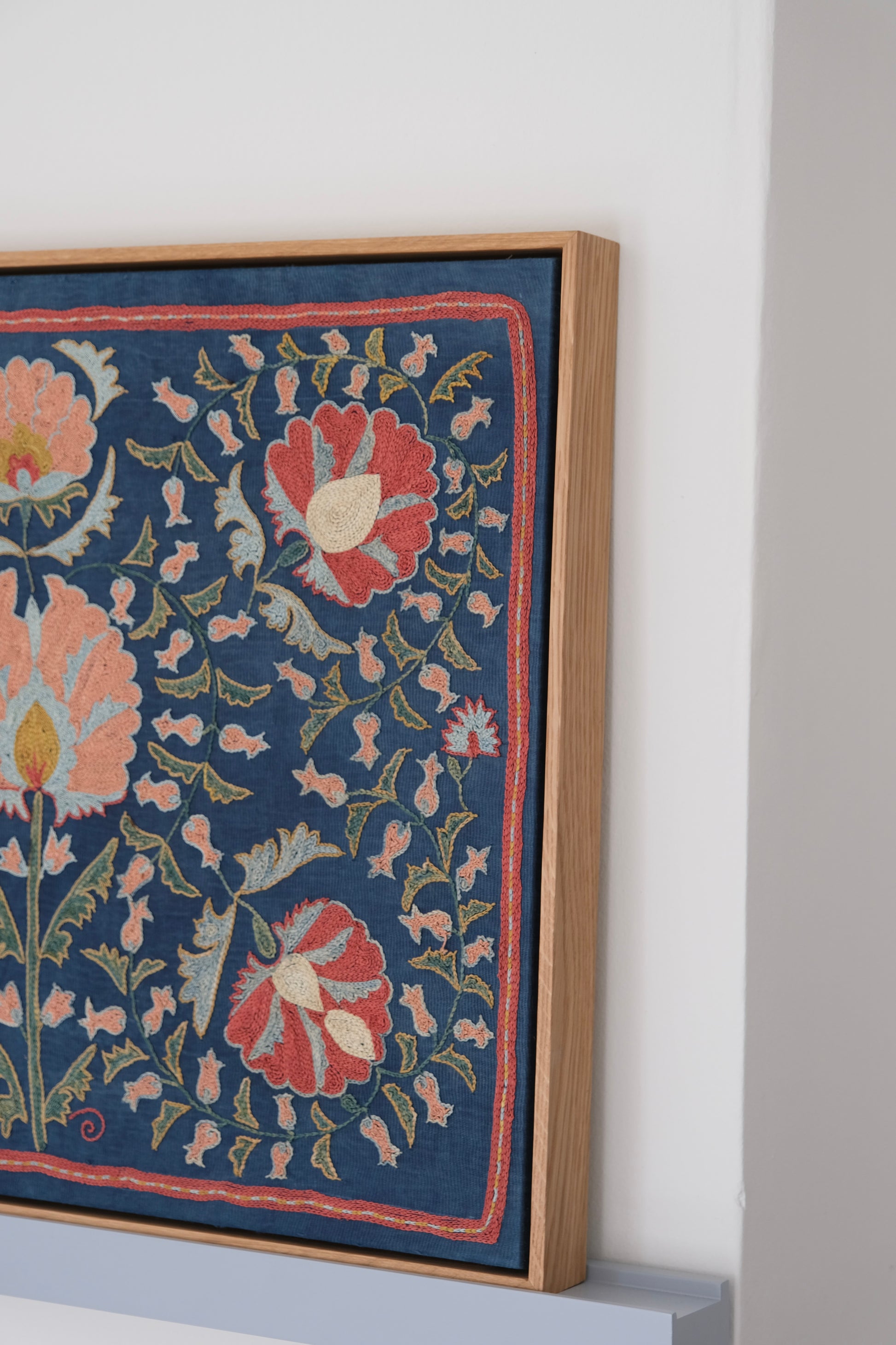 Framed suzani, embroidered textile art, wooden frame, navy blue with floral motifs, side view