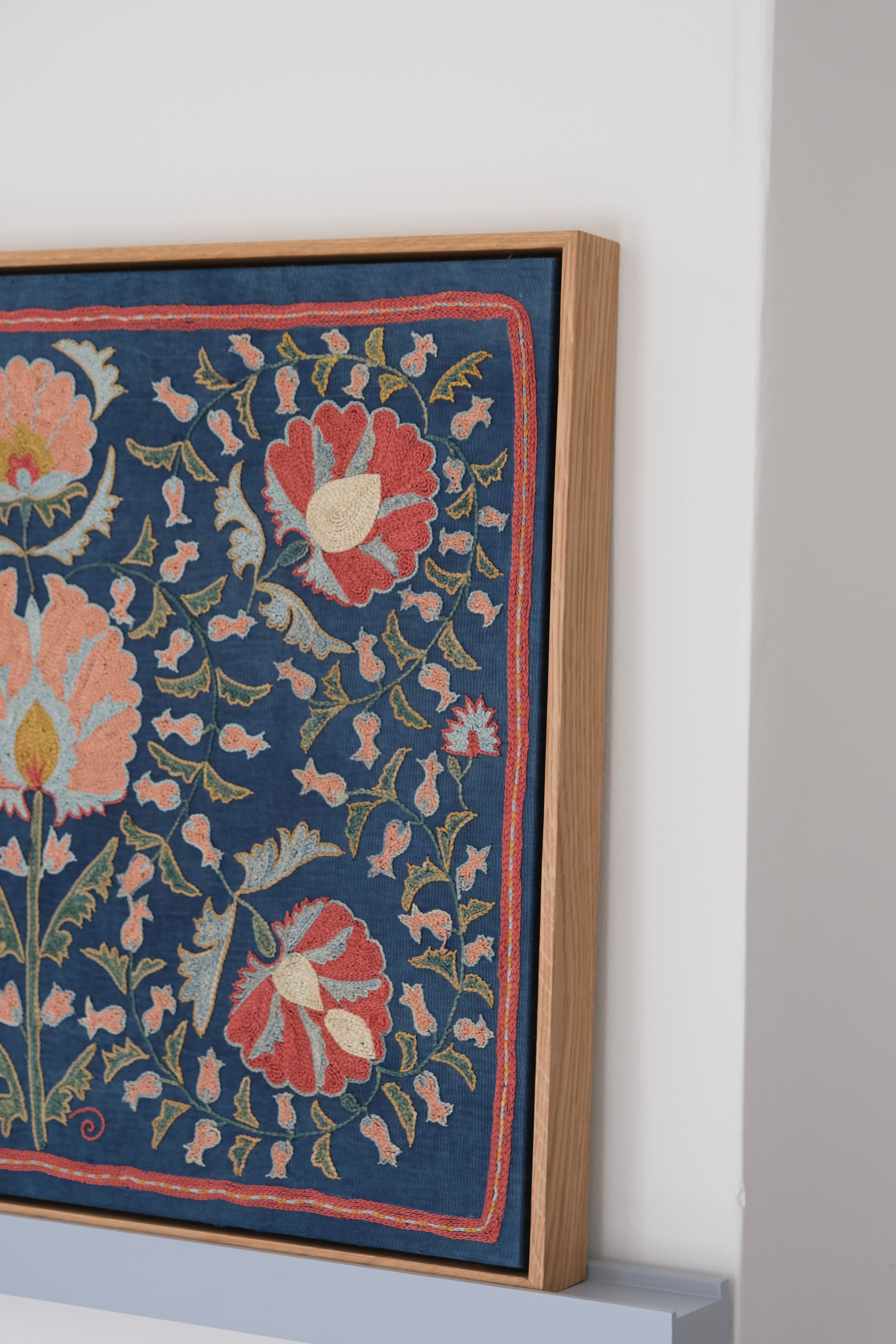 Framed suzani, embroidered textile art, wooden frame, navy blue with floral motifs, side view