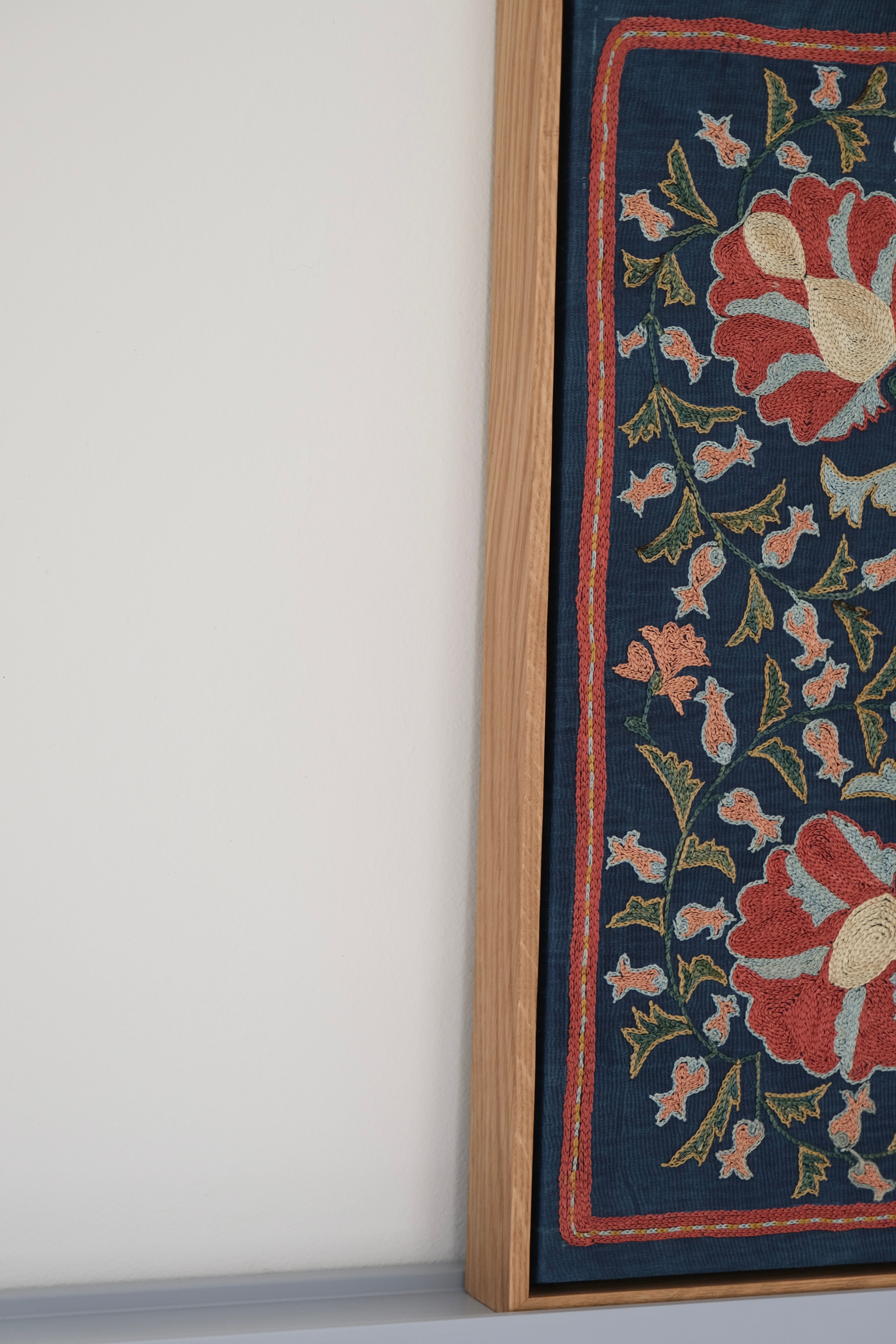 Framed suzani, embroidered textile art, wooden frame, navy blue with floral motifs, side view