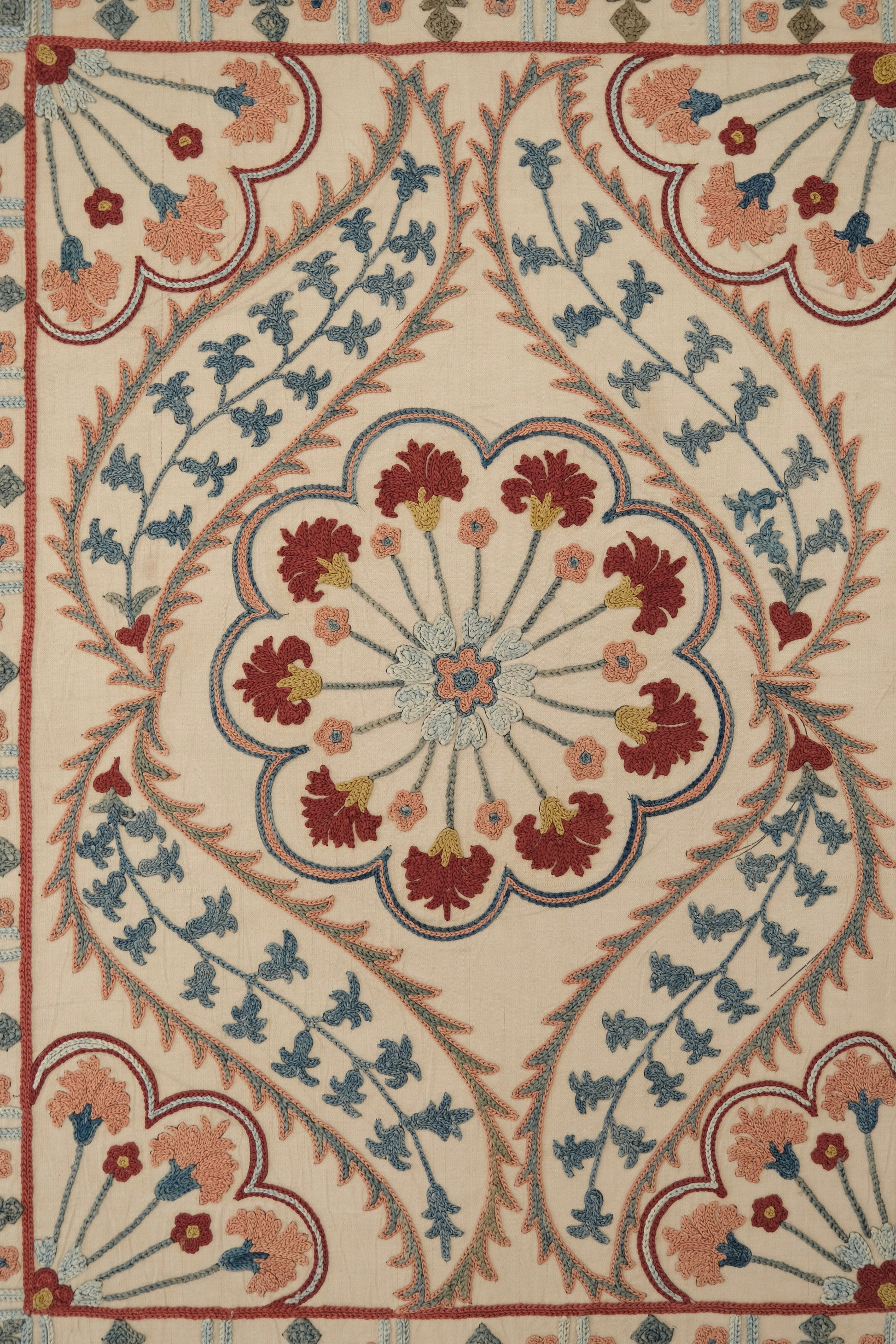 Framed suzani, embroidered textile art, wooden frame, white with blue and pink design, close-up