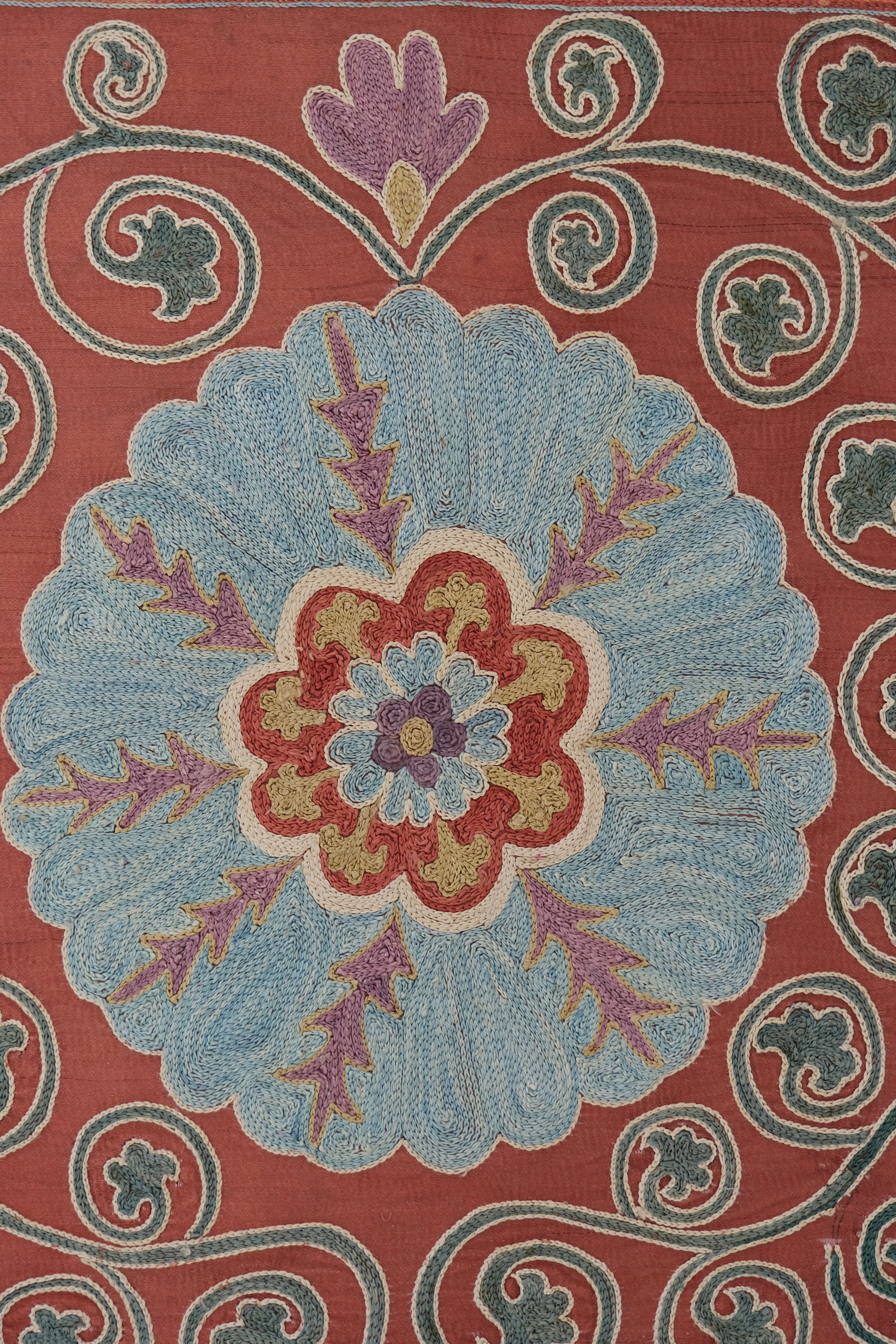 Framed suzani, embroidered textile art, wooden frame, dark orange and blue floral design, close-up