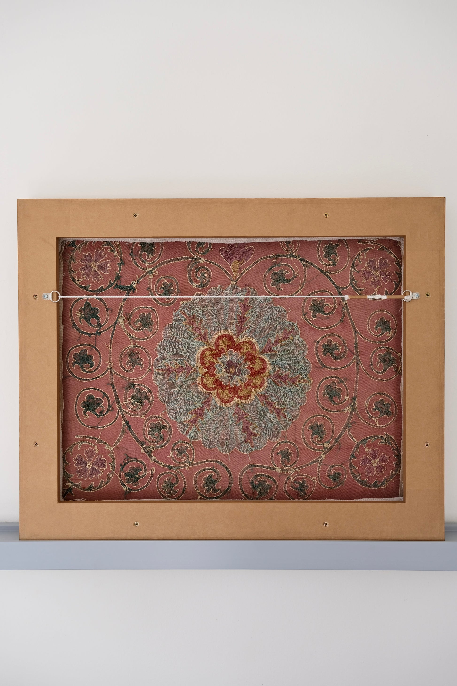 Framed suzani, embroidered textile art, wooden frame, dark orange and blue floral design, backside
