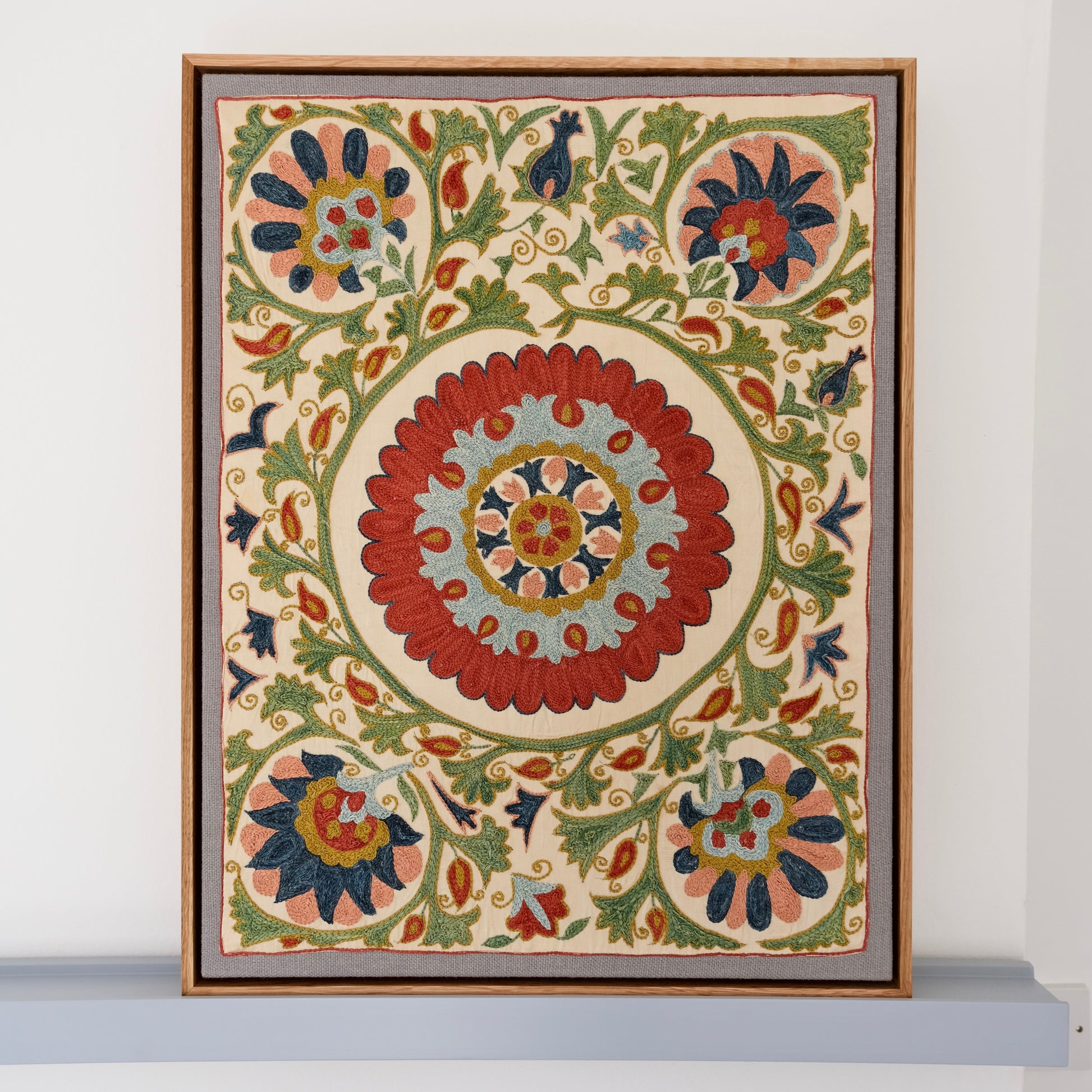 Framed suzani, embroidered textile art, wooden frame, white with green, blue and red floral design