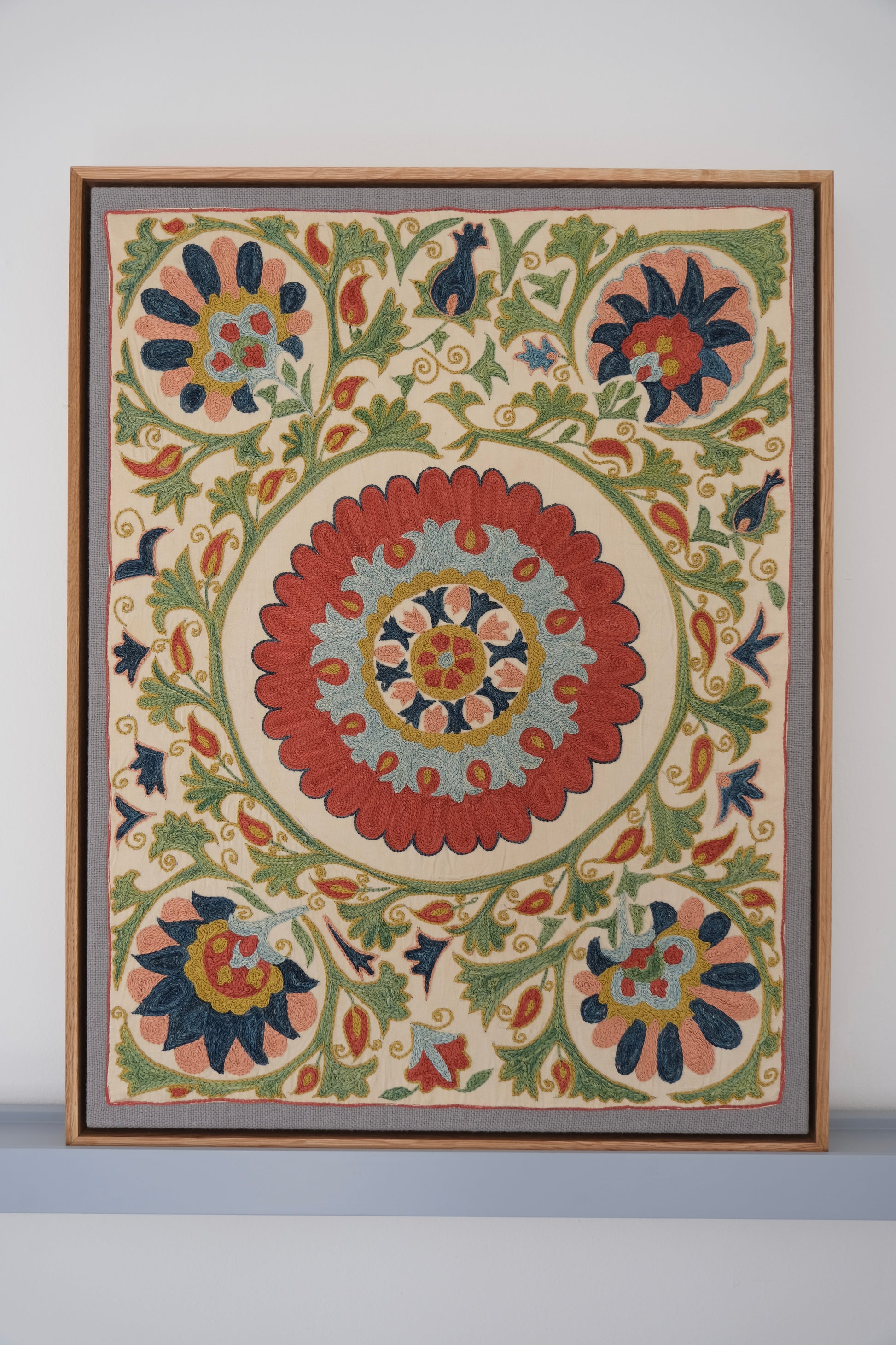 Framed suzani, embroidered textile art, wooden frame, white with green, blue and red floral design
