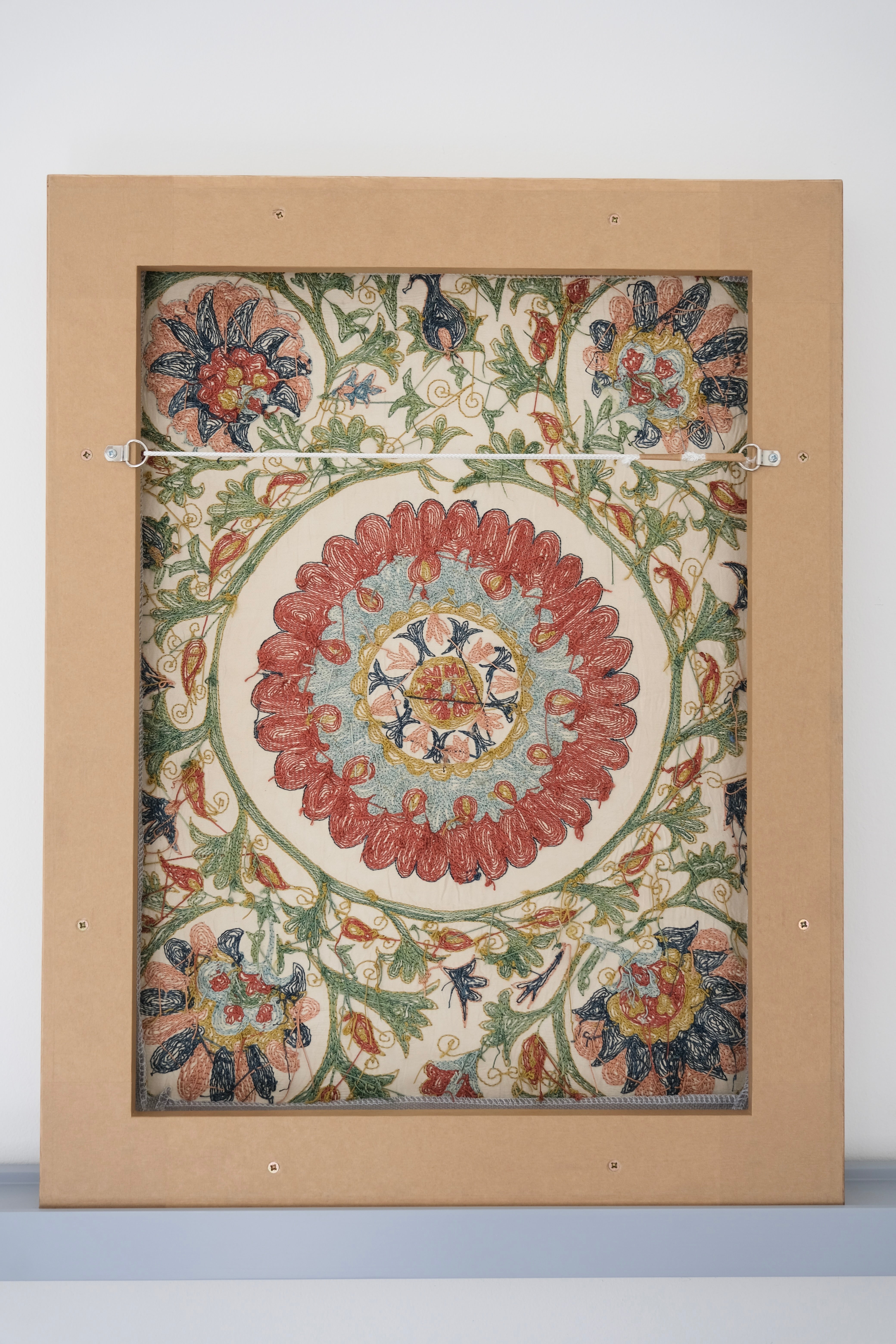 Framed suzani, embroidered textile art, wooden frame, white with green, blue and red floral design, backside
