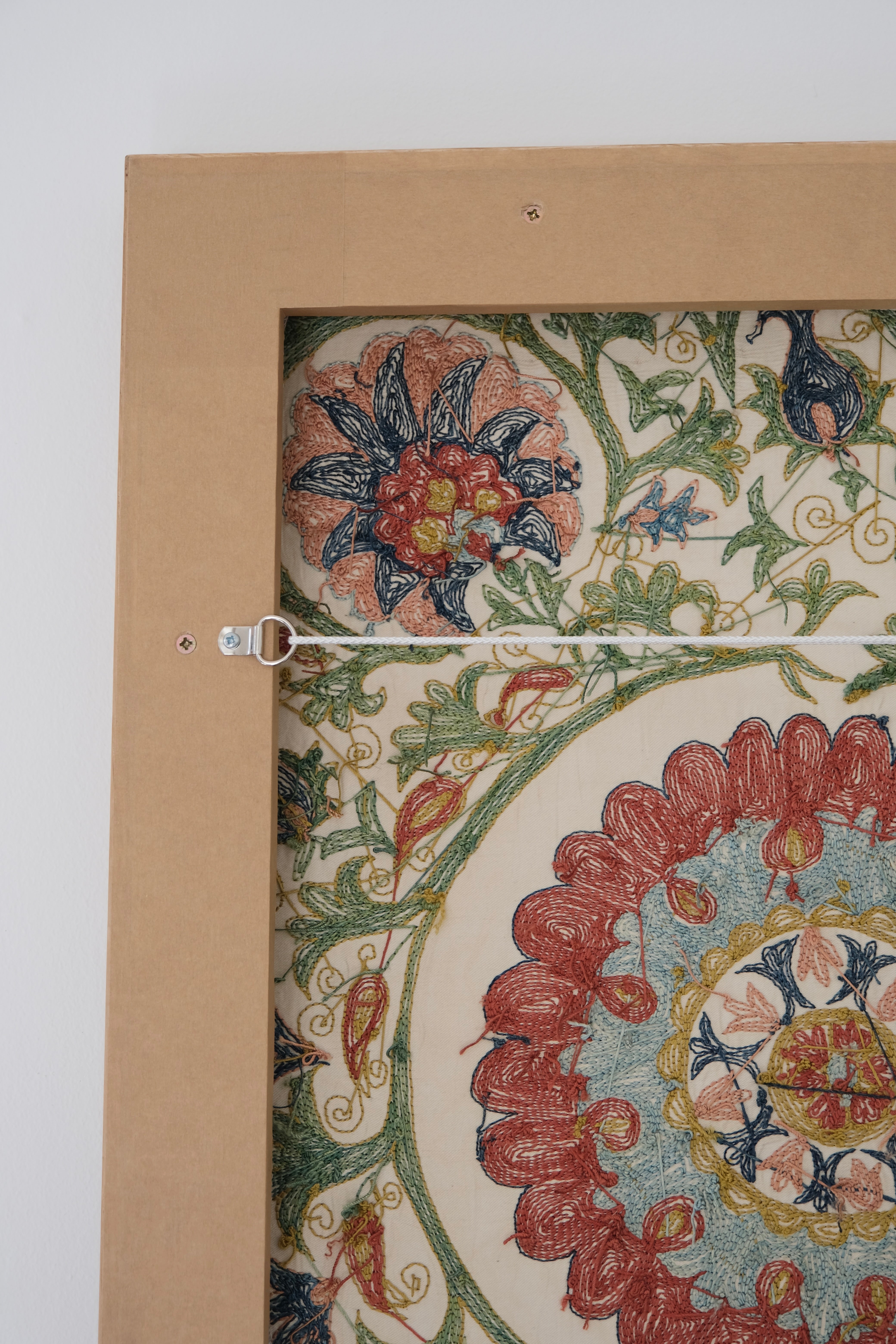 Framed suzani, embroidered textile art, wooden frame, white with green, blue and red floral design, backside