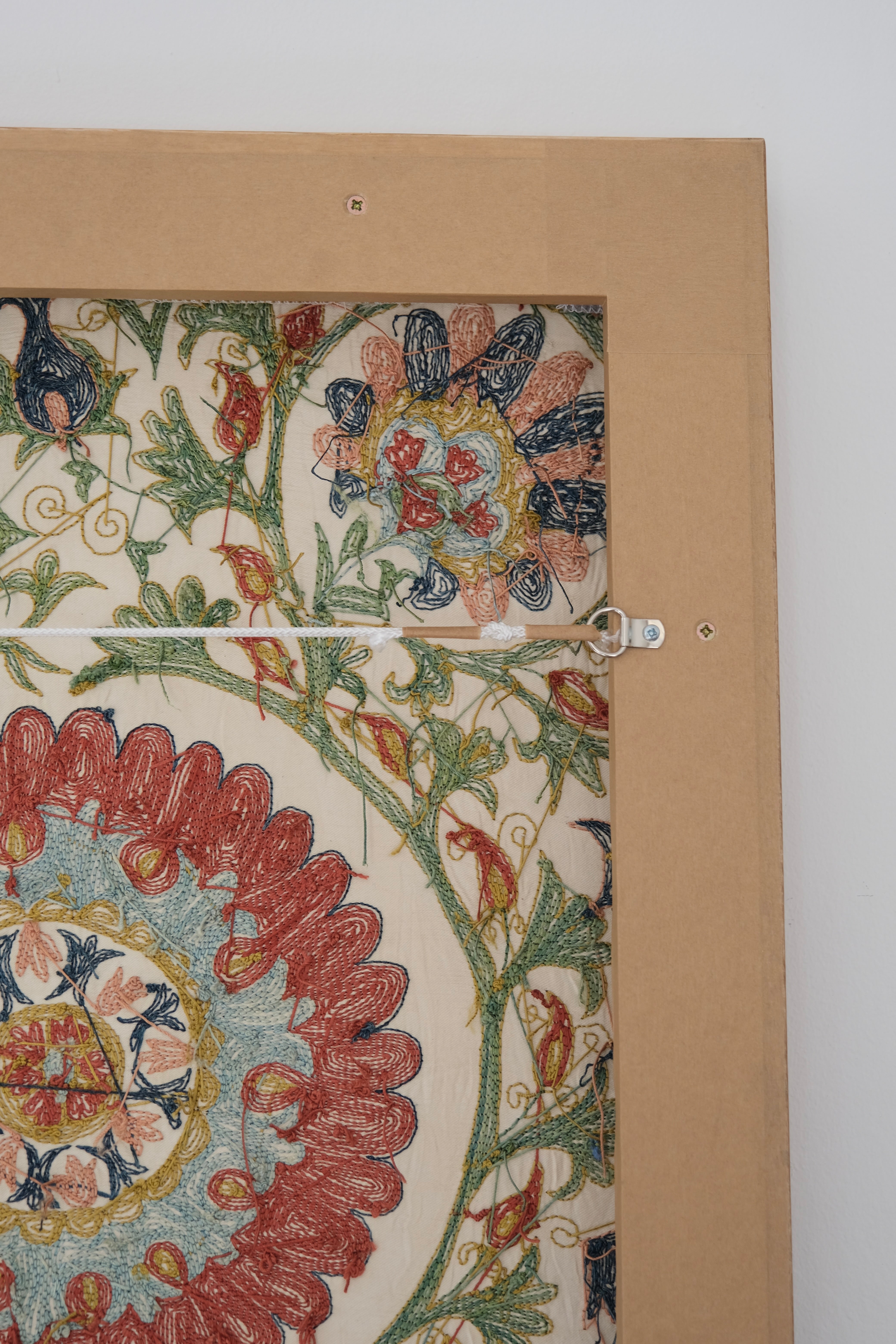 Framed suzani, embroidered textile art, wooden frame, white with green, blue and red floral design, backside