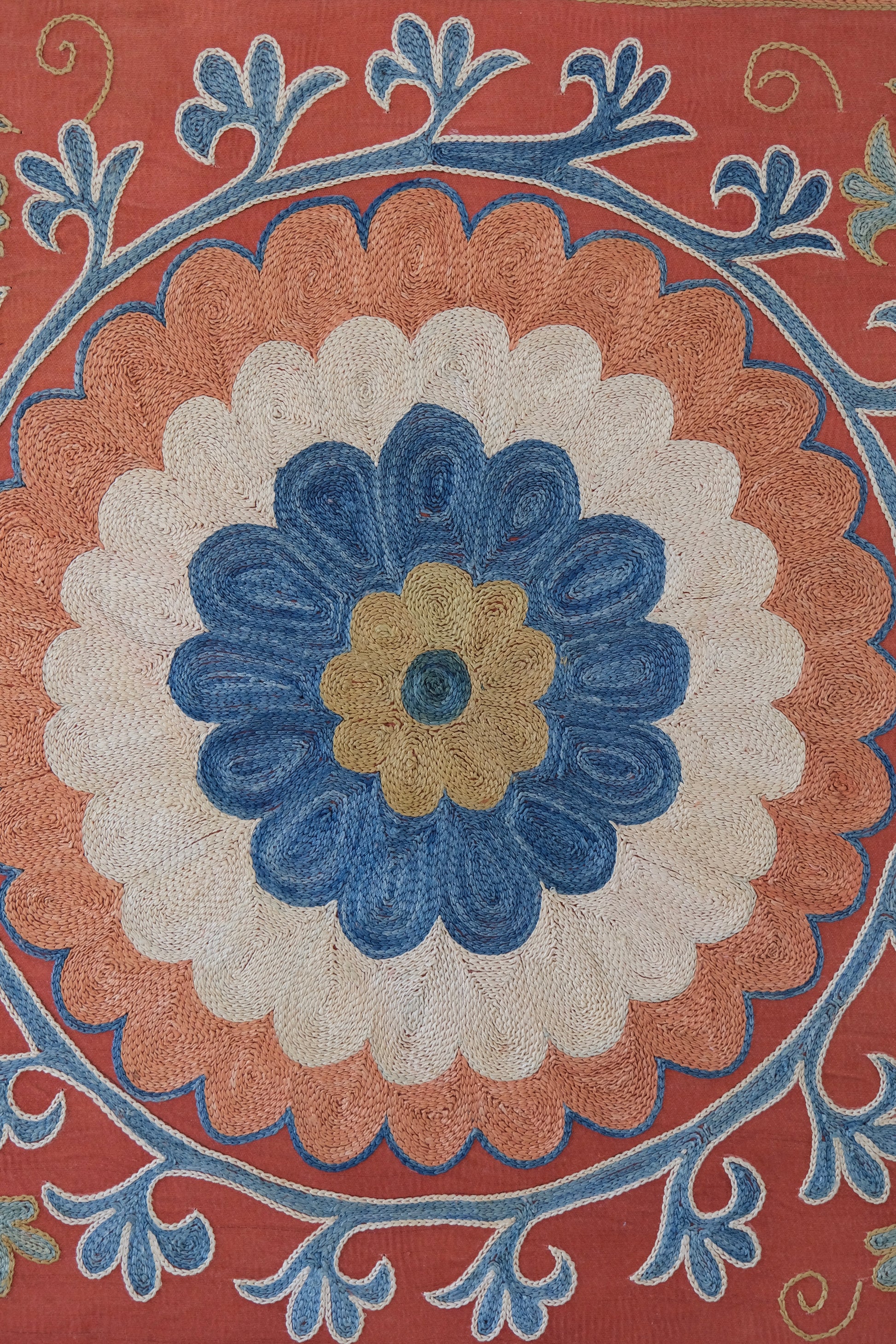 Framed suzani, embroidered textile art, wooden frame, dark orange with blue and green floral motifs, close-up